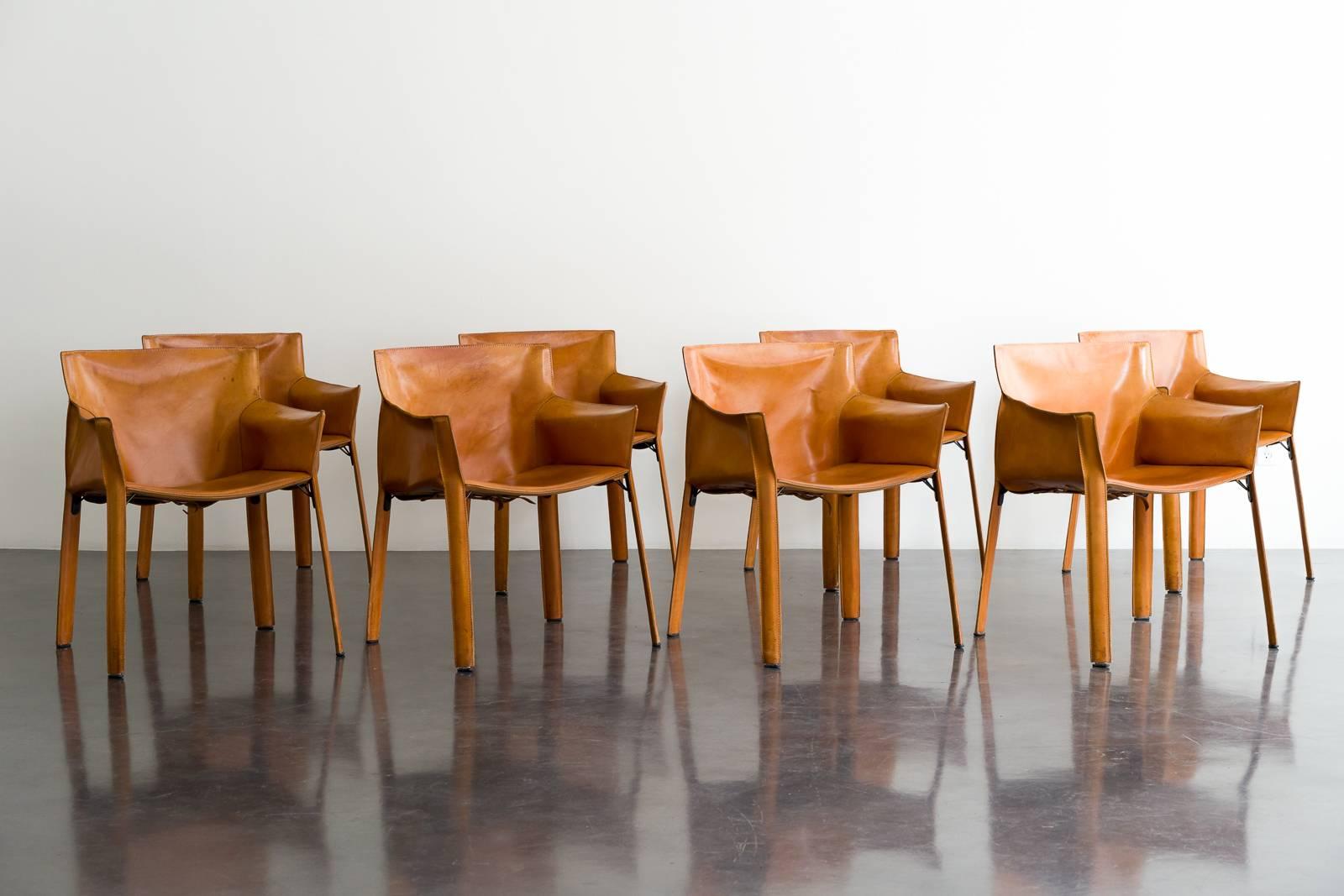 A beautifully patinated set of eight saddle leather armchairs designed by Giancarlo Vegni for Fasem in 1982. A more modern and graceful design than the CAB chairs by Mario Bellini from the decade prior, the similarly stitched hide over steel frame