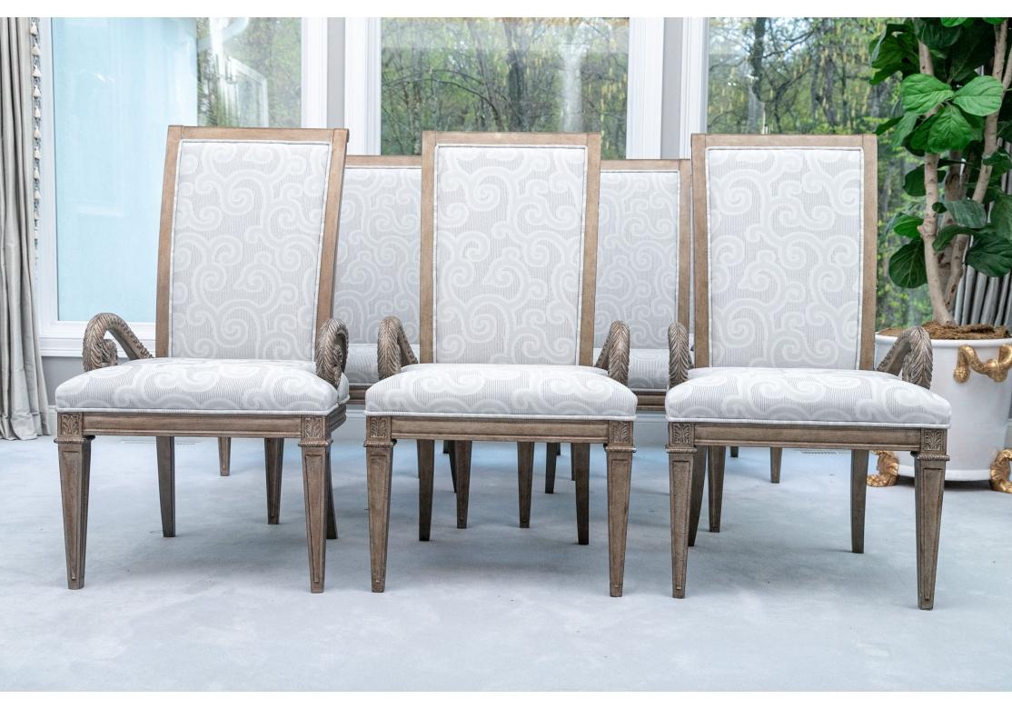 Set of 8 upholstered dining chairs with high rectangular backrests, lavishly covered in finely ribbed textured fabric in silver/grey/taupe and accentuated with thick welt trim. The chairs with dramatic serpentine carved plume arms, palmette carved
