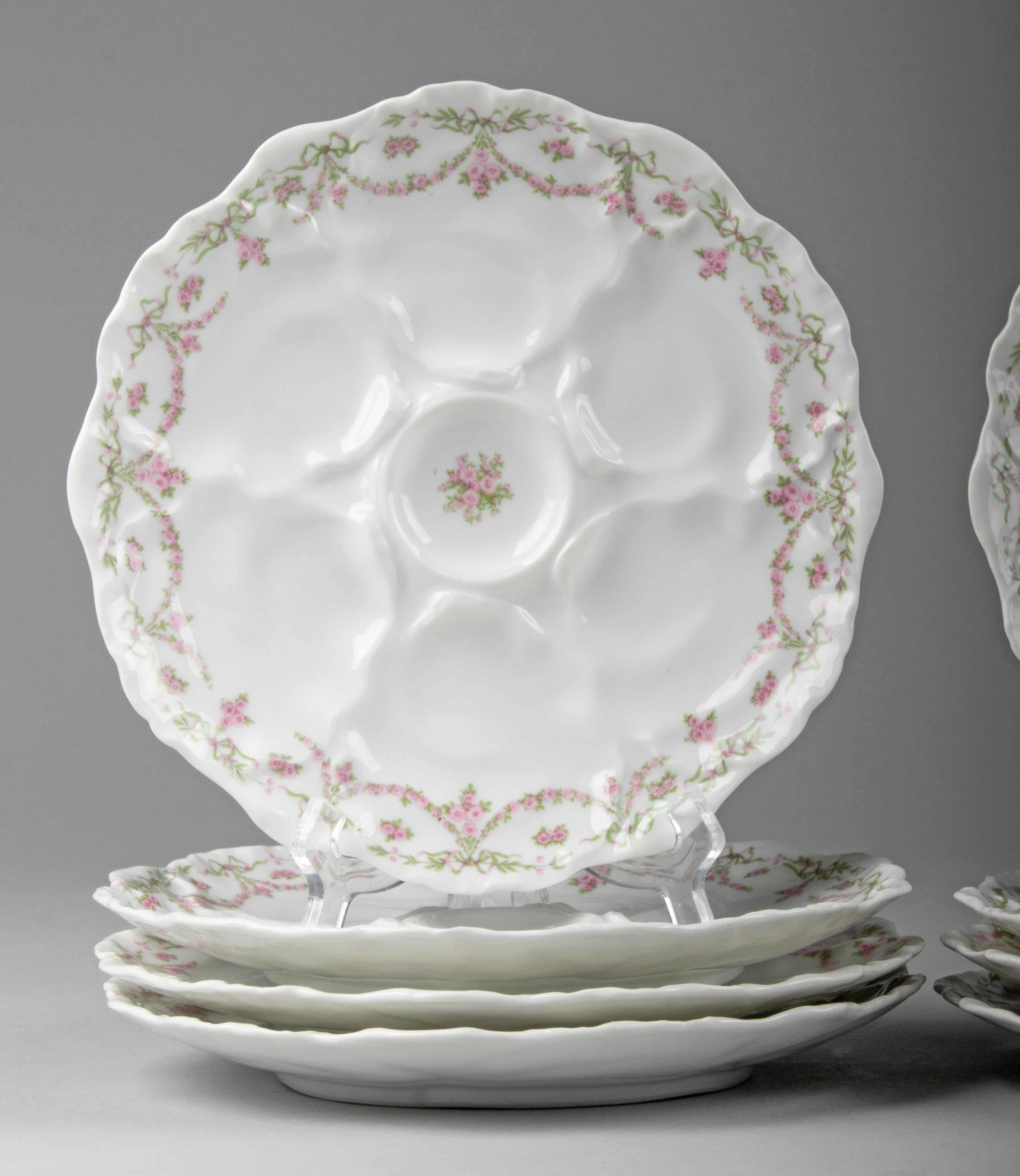 Beautiful set of 8 porcelain oyster plates from the French brand Limoges. The plates have room for six oysters each. The porcelain is decorated with garlands and fine roses. All plates are marked on the back. The set is in good condition. No chips