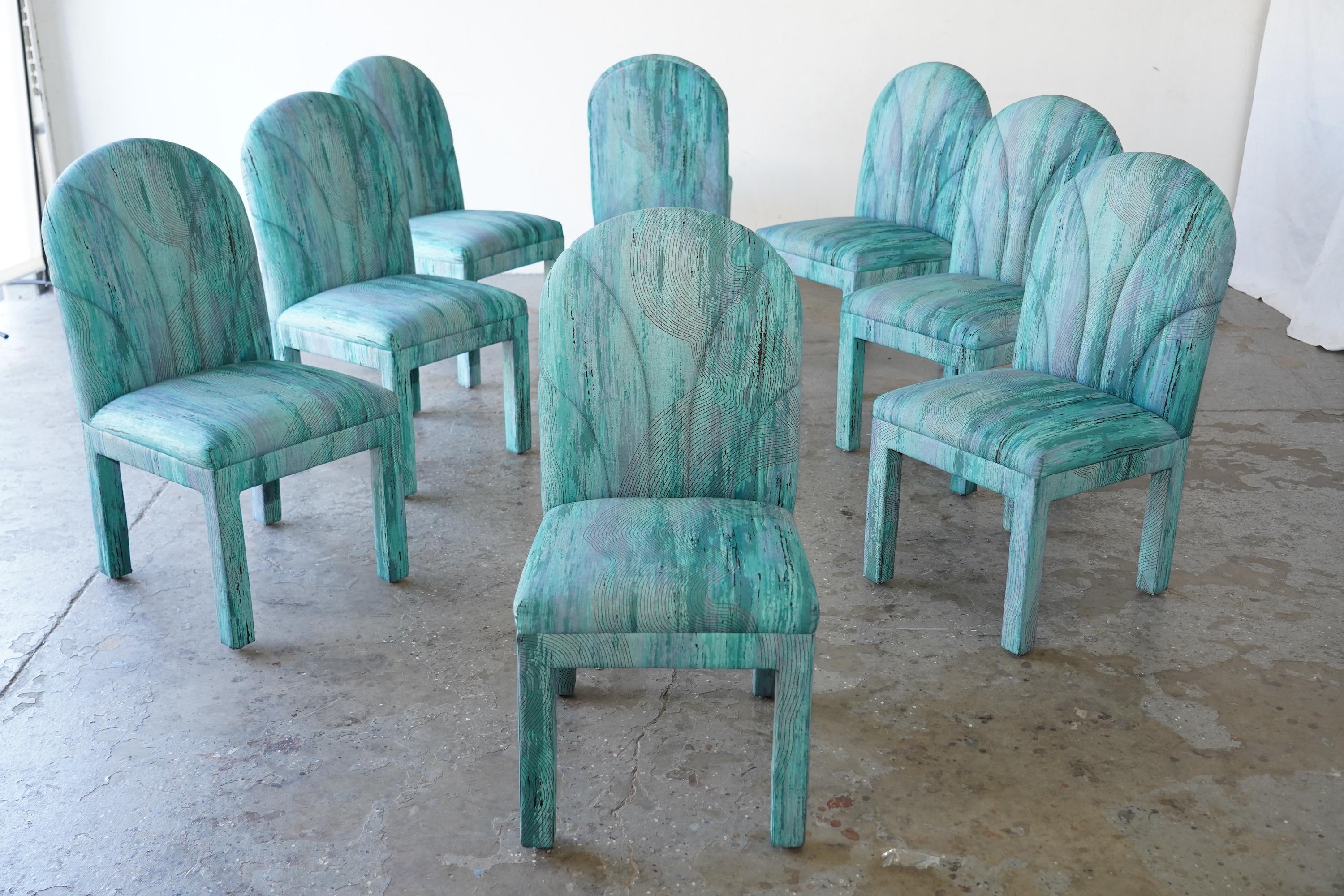 Un impresionante conjunto de ocho sillas de comedor vintage, de los años 1980-1990, que muestran un atrevido diseño posmoderno. Las sillas presentan esculturales respaldos arqueados y armazones totalmente tapizados, envueltos en un vibrante tejido