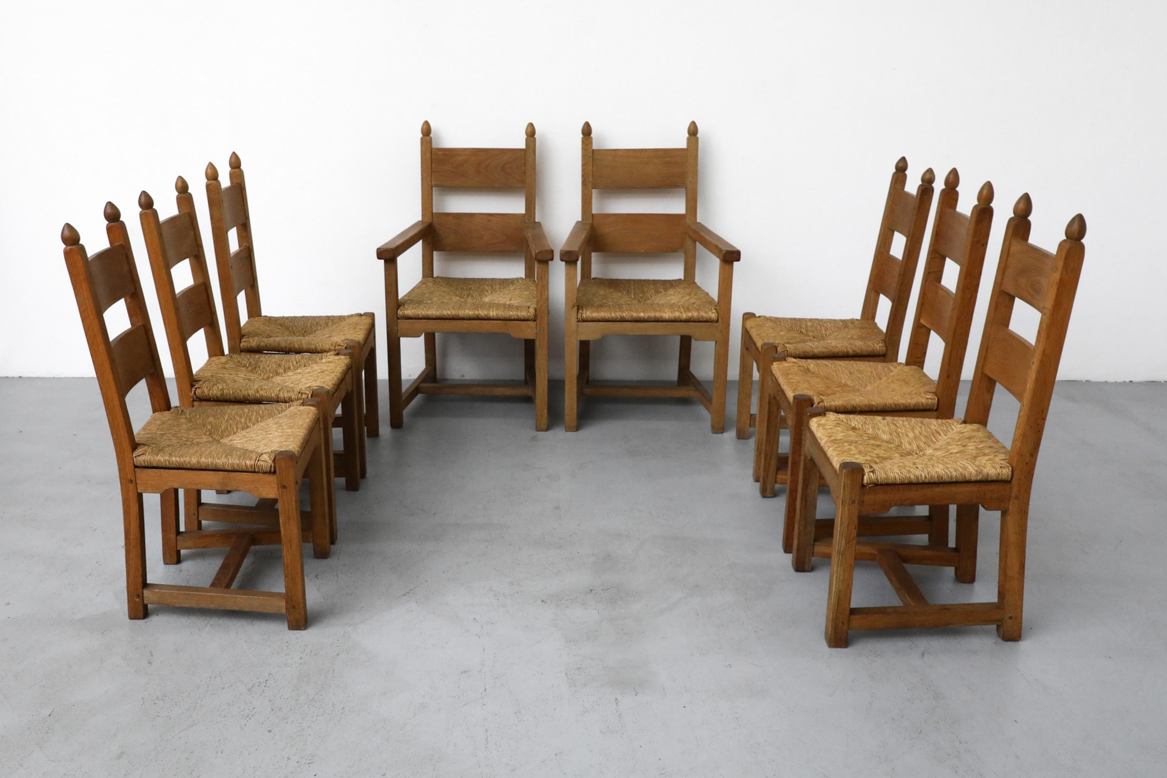 Set of 8 handsomely made, Quaker style dining chairs with hand-woven rush seats. The set comes with two larger captain's chairs with armrest and six smaller, armless side chairs. All chairs are made from solid oak with decoratively carved tops. Side