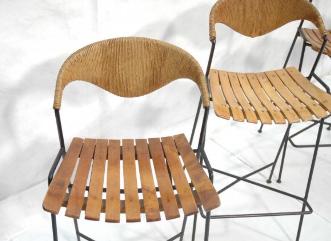 A set of eoght (8) stylish stools with wood slatted seat, rattan back and black metal base.  USA, circa 1950.

Priced at $850 per stool or $6,800 as a set of eight; contact us to specify a different quantity.