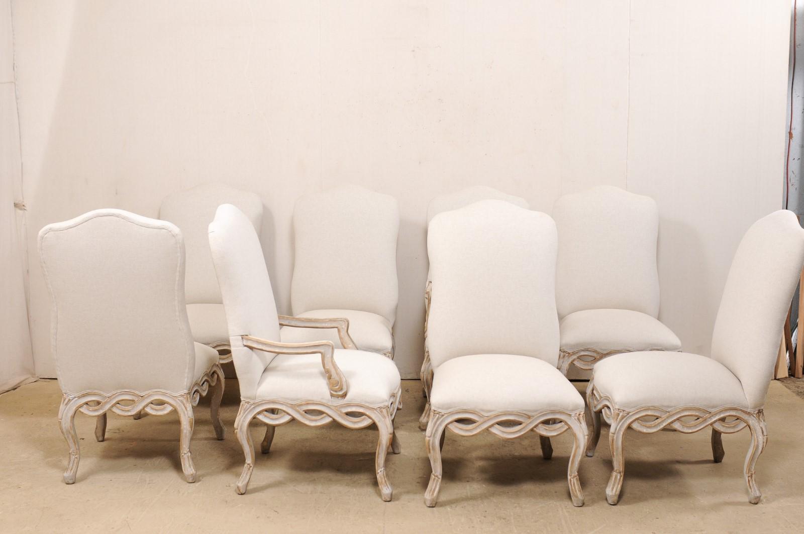 A set of eight American made, Italian Venetian style, carved wood dining chairs with upholstered seats and backs. This vintage set of dining chairs have been beautifully crafted in a Venetian Italian style, and feature subtle hourglass-shaped