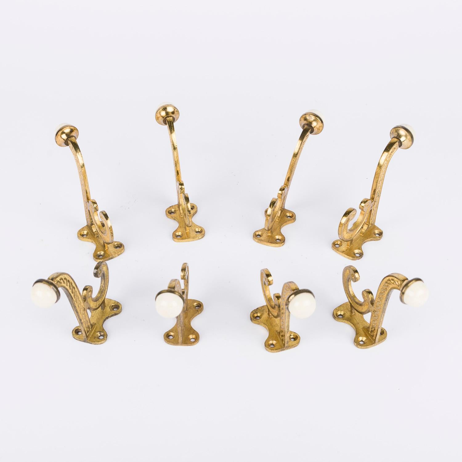 A set of 8 Victorian gilt brass hooks with white porcelain finials.

Can be wall or door mounted for hanging of coat, hats, etc.

Projection from wall: 4 inches - 10 cm.