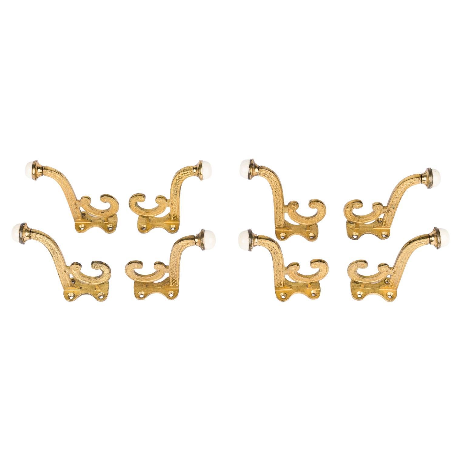 Set of 8 Victorian gilt brass hooks with white porcelain finials. For Sale