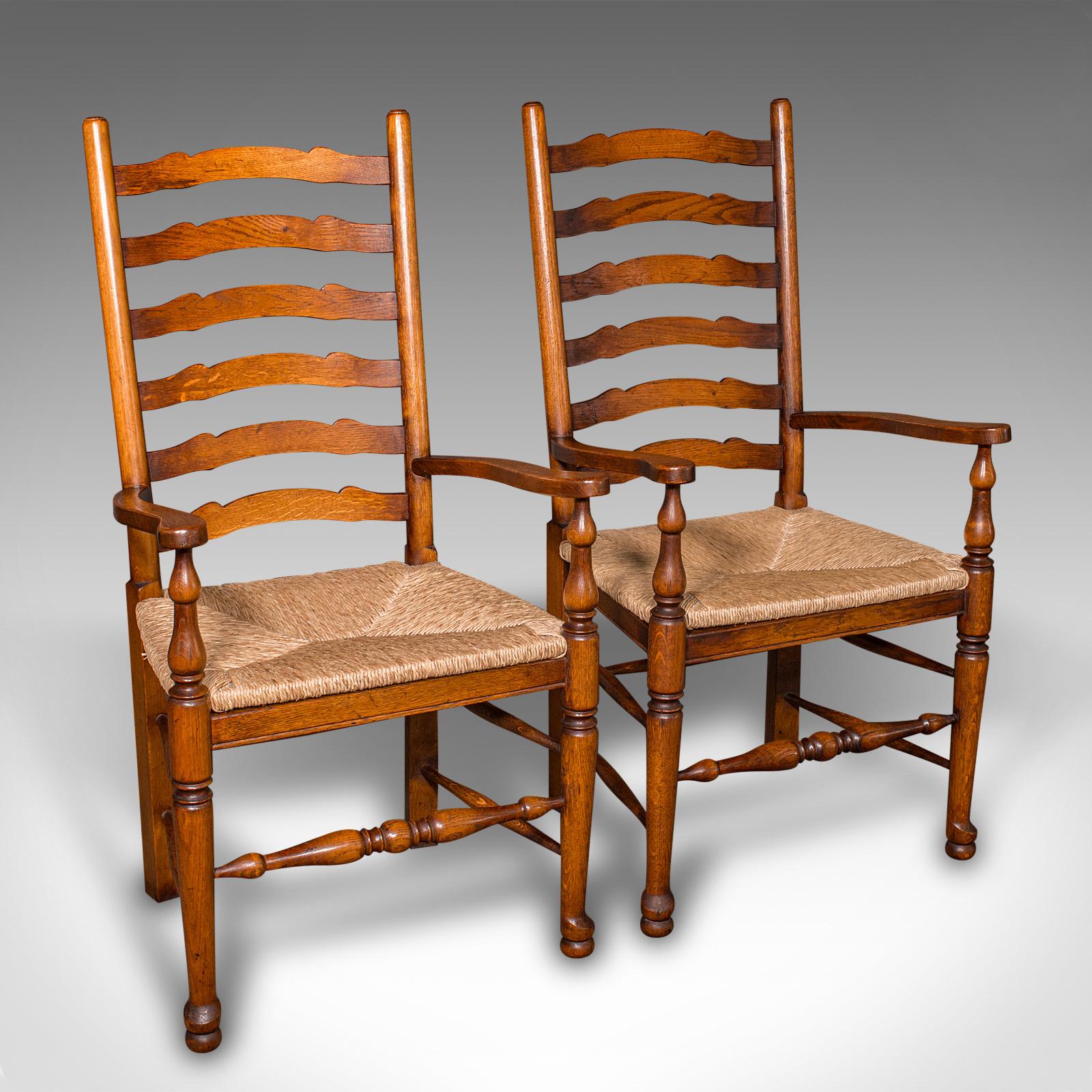 
This is a superior set of 8 vintage ladder back dining chairs. An English, oak carver and rush seat suite in Georgian revival taste, dating to the late 20th century, circa 1980.

Appealing revival taste with a traditional country house