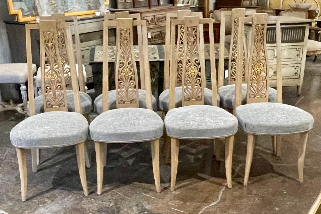 Decorative set of 8 vintage French hand carved high back dining chairs. Interesting pattern on the carvings and pretty bleached wood patina. The chairs are upholstered in a nice neutral blue woven fabric. Very unique and beautiful!.