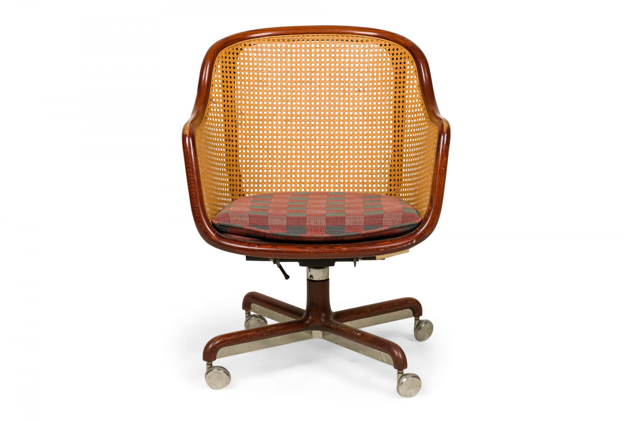American Mid-Century swiveling rolling office / conference chair with an ash bentwood frame, caned sides and backs, and a muted blue and red plaid upholstered seat, resting on a four leg ash and silver metal base ending in four silver metal casters.