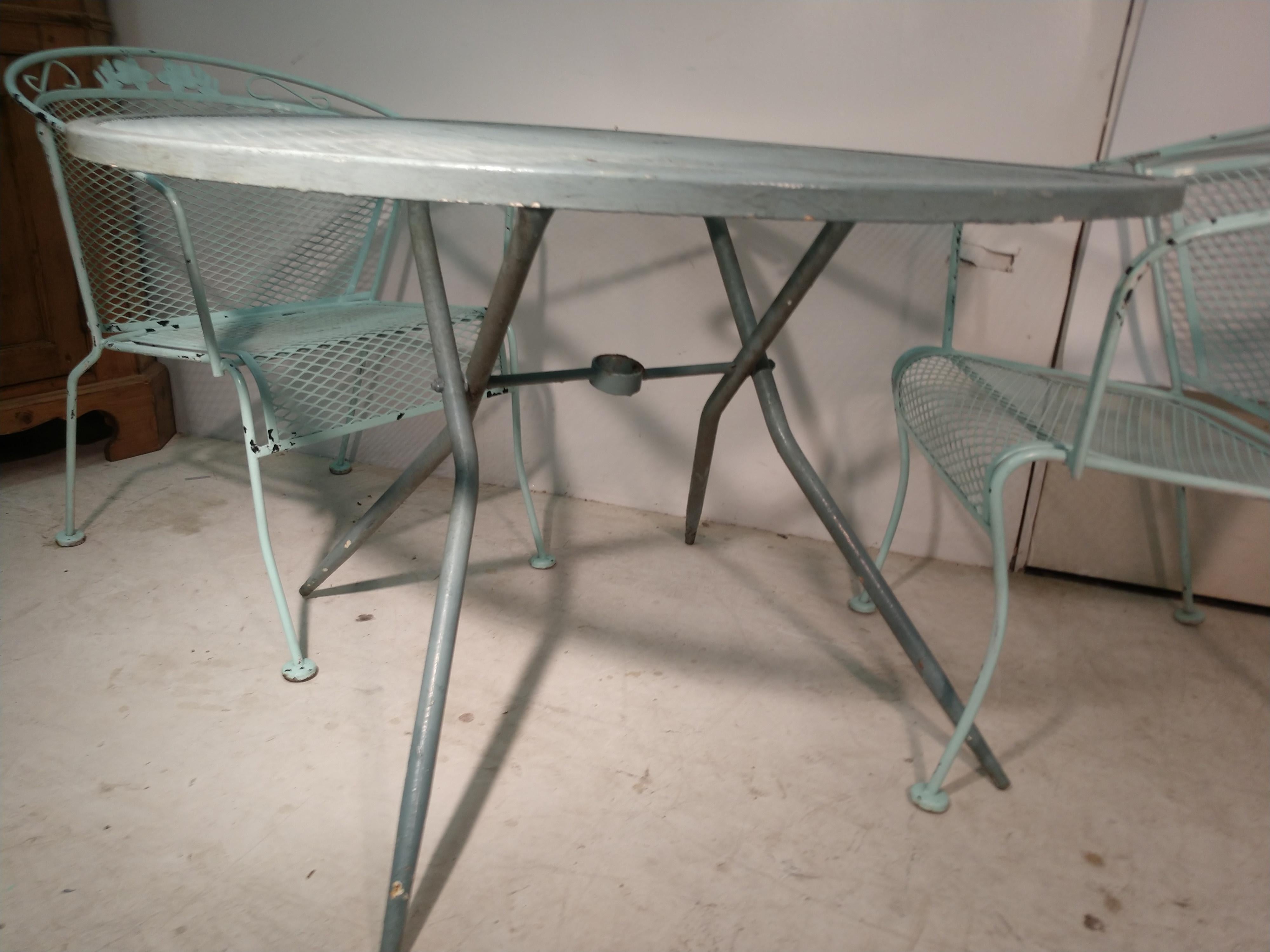 Fabulous set of 8 iron mesh chairs with arms from the Woodard Outdoor furniture co. circa 1960. Iron table with mesh top is 42in. round. Chairs are very comfortable and structurally sound with no rust.