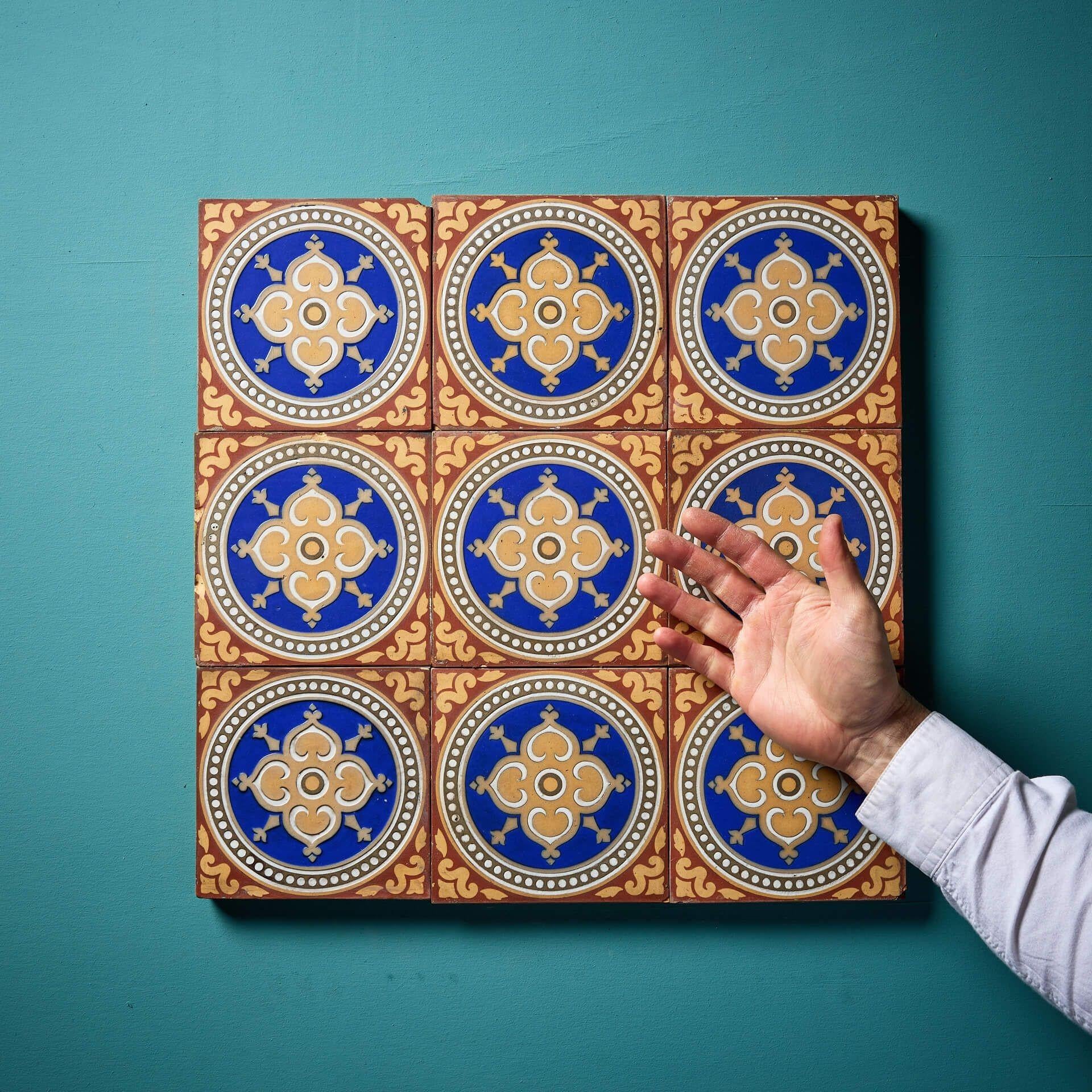 Neuf carreaux à l'encaustique Maw & Co de 6 pouces présentant des motifs rouges et chamois entourant des rondeaux à glaçure bleue autour d'un fleuron central.

Cet ensemble de neuf carreaux récupérés peut être utilisé de différentes manières,