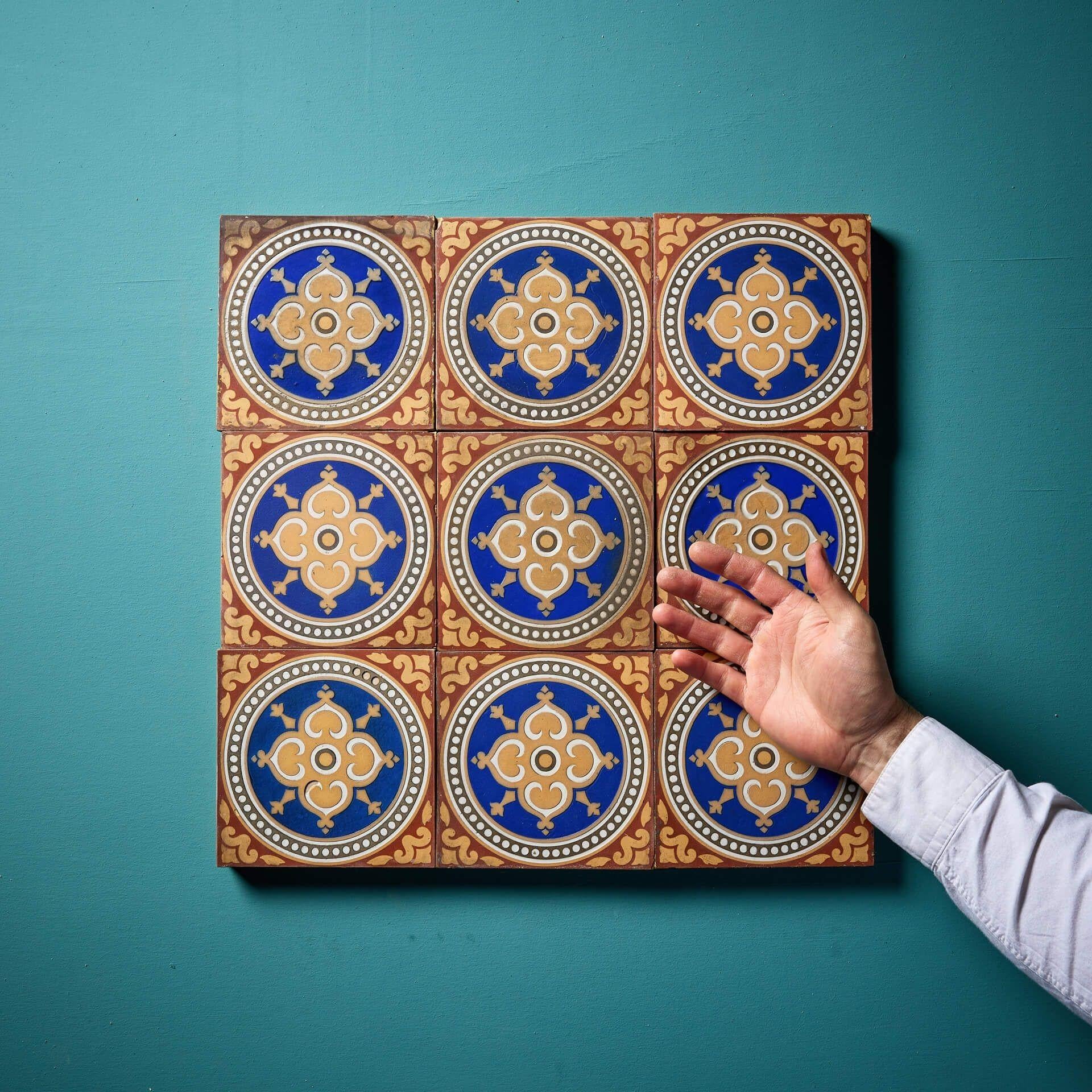 Nove antiche piastrelle ad encausto di Maw & Co da 6 pollici che presentano motivi rossi e colorati che circondano tondi con smalto blu intorno a una cimasa centrale.

Questo set di nove piastrelle di recupero può essere utilizzato in molti modi,