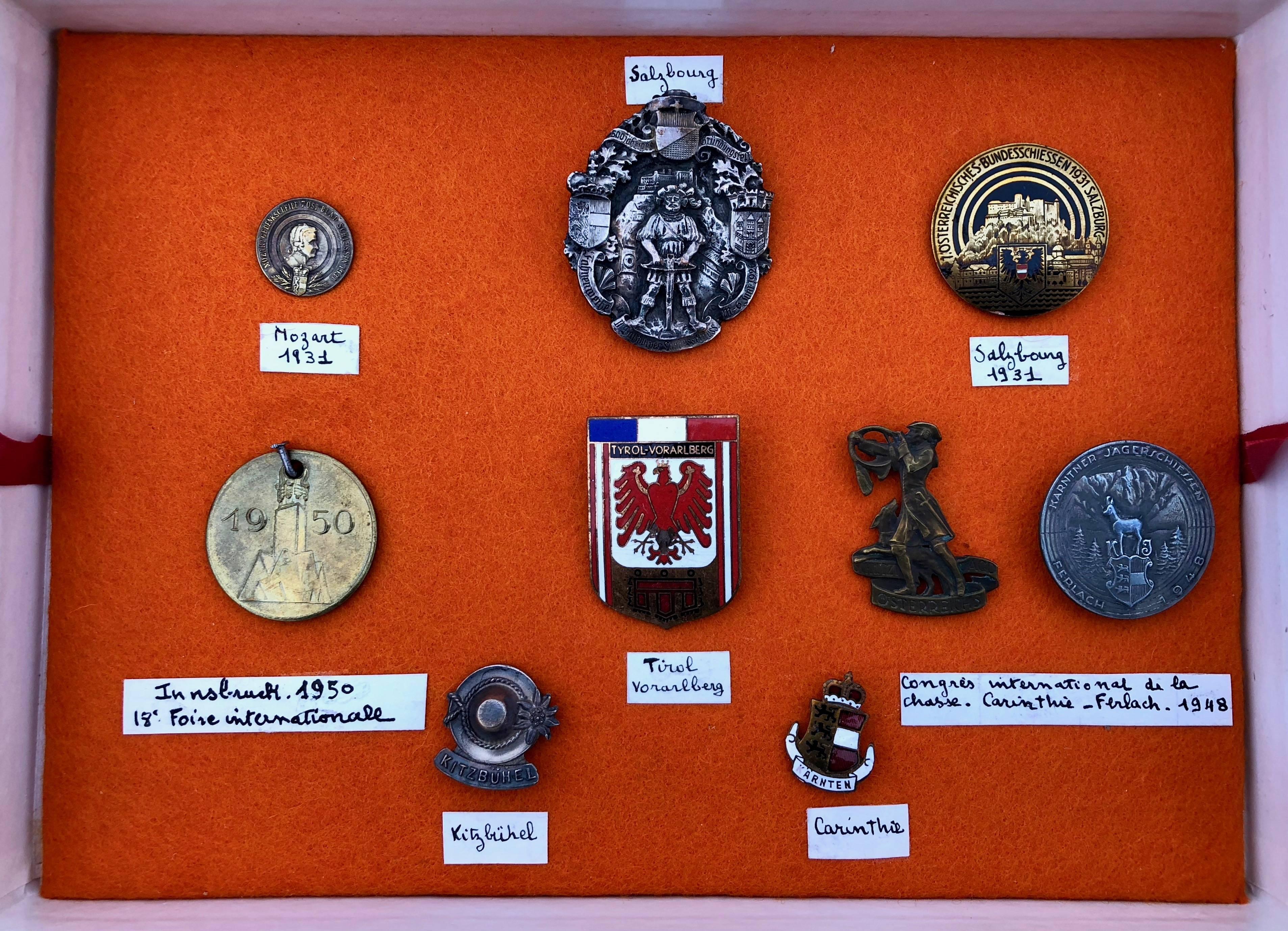 This is a unique set of nine Austrian commemorative medals in a display box with orange background, black box exterior with green trim, interior lift taps and French block writing 
