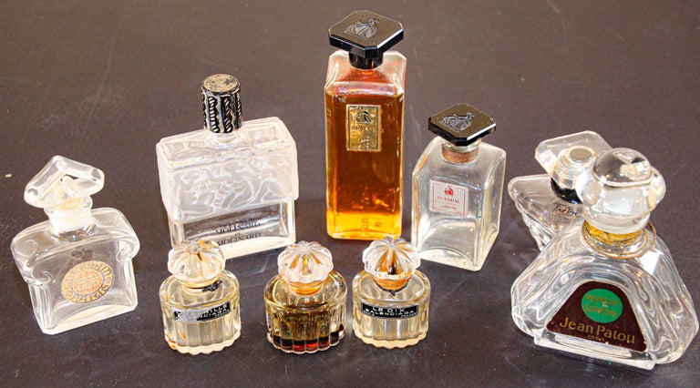VIntage lot of 9 collectible perfume bottles by Lalique, including 1 square 'Molinard de Molinard' in frosted glass relief decoration depicting nude figures embossed 'Lalique' on underside. 
Lalique for Molinard Perfume Bottle Collector.
Lalique