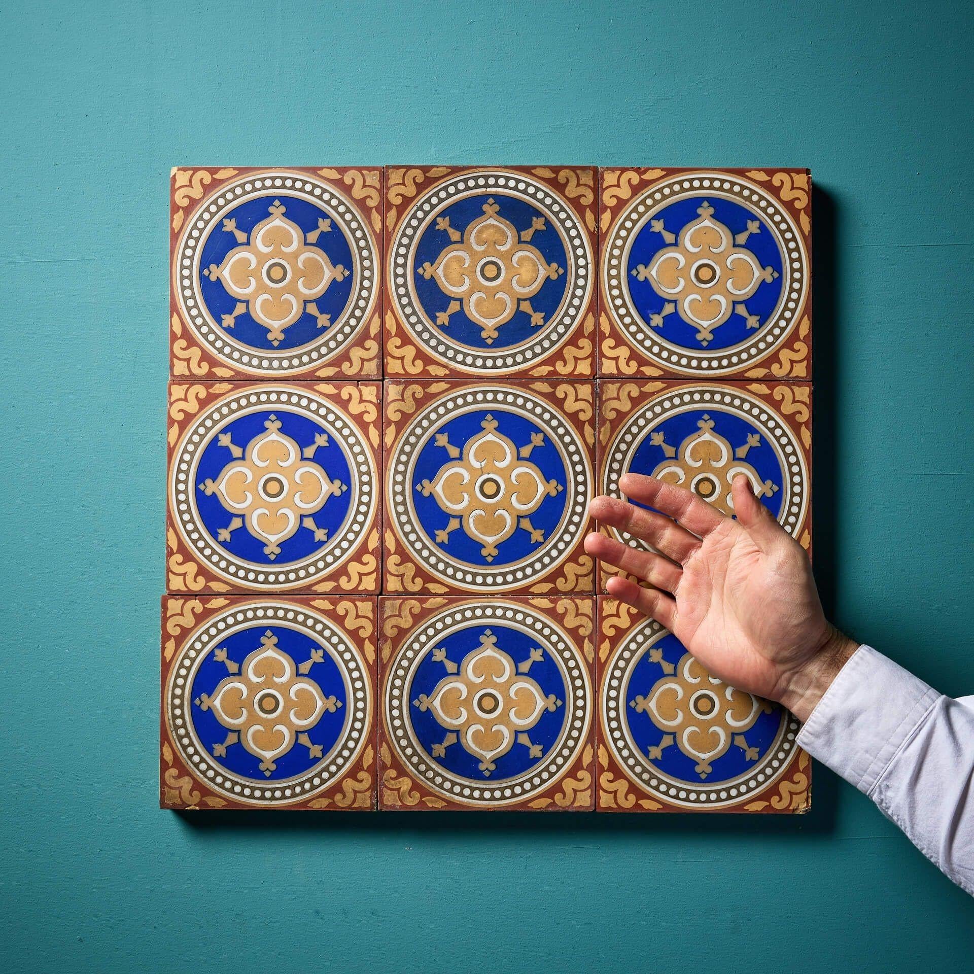 Nine 6-inch patterned Maw & Co encaustic tiles (stamped) displaying red and buff patterns surrounding roundels with blue glaze around a central floret. This is just one of various sets of these tiles we are selling, sold in batches of 9 as