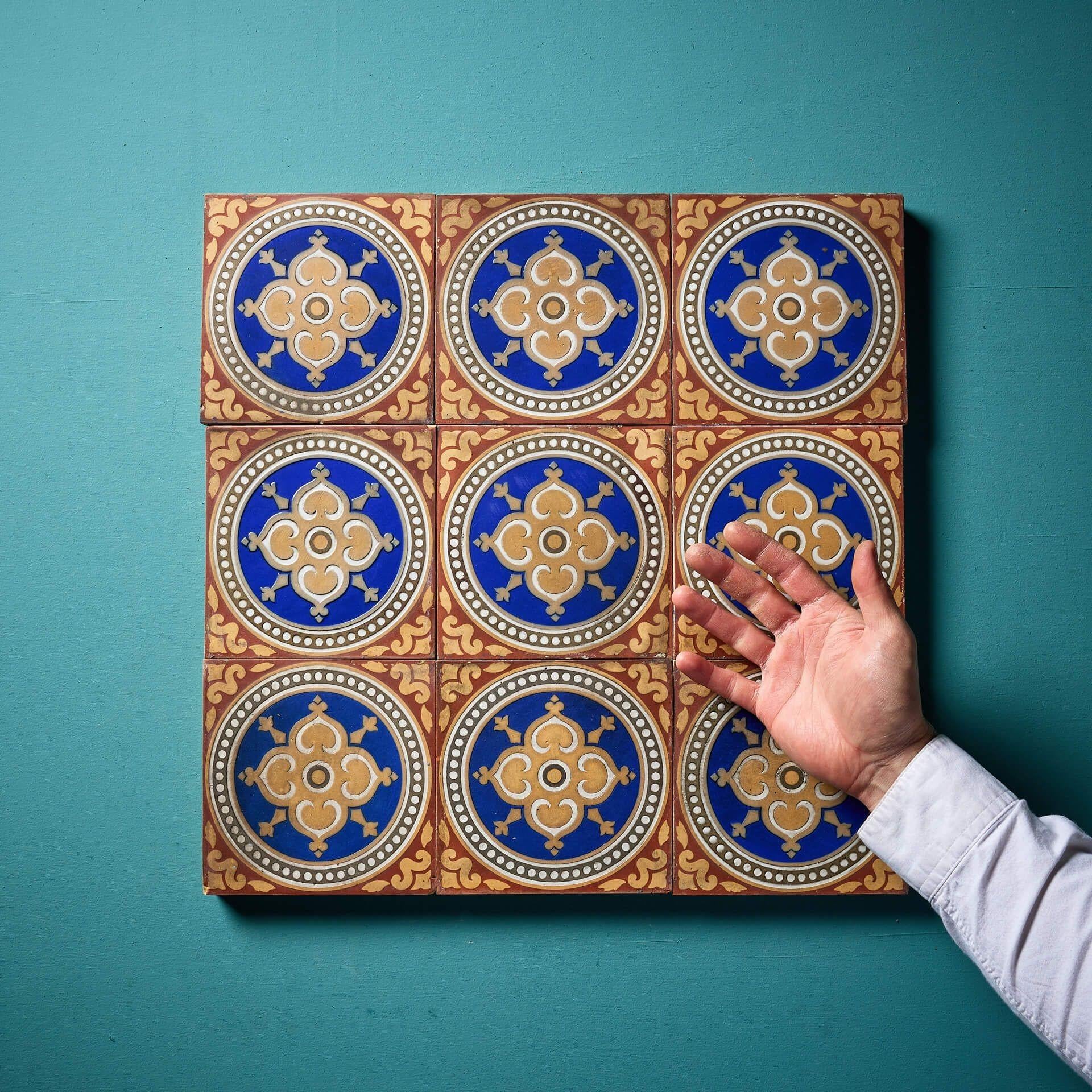 Nine 6-inch patterned Maw & Co encaustic tiles (stamped) displaying red and buff patterns surrounding roundels with blue glaze around a central floret. This is just one of various sets of these tiles we are selling, sold in batches of 9 as