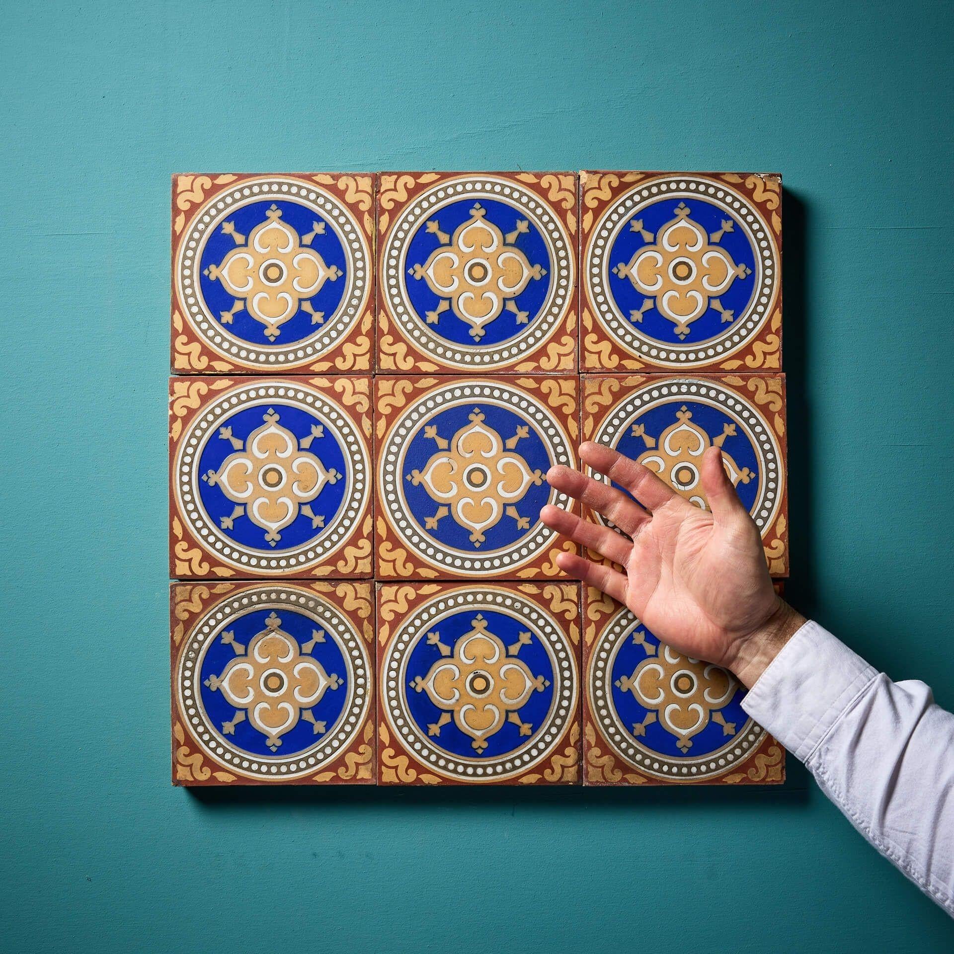 Nine 6-inch reclaimed Maw & Co encaustic tiles (stamped) displaying red and buff patterns surrounding roundels with blue glaze around a central floret. This is just one of various sets of these tiles we are selling, sold in batches of 9 as