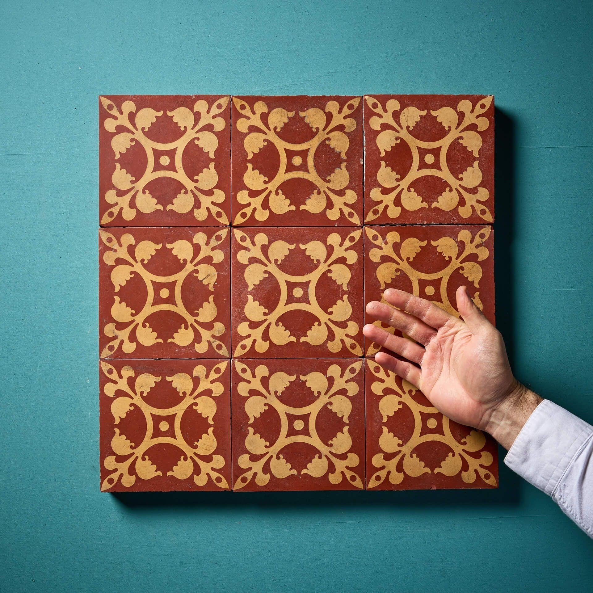 Un set di nove vivaci piastrelle gotiche ad encausto recuperate di Minton & Co (timbrate), circa 1840-1860. Ciascuna piastrella da 6 pollici è decorata con toni di terracotta rossa e marrone per creare una croce ordinata e fogliare; il set