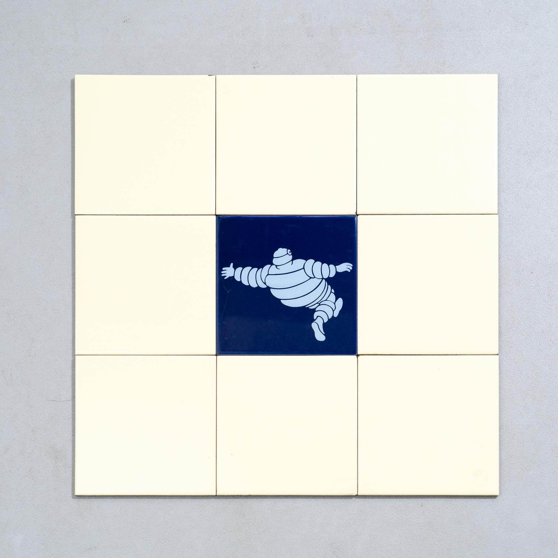 Embark on a journey of vintage charm with this exceptional set of nine tiles, featuring the iconic Michelin Man in a vibrant blue centerpiece, surrounded by original yellow tiles. Crafted by an unknown manufacturer in Spain circa 1960, this set is a