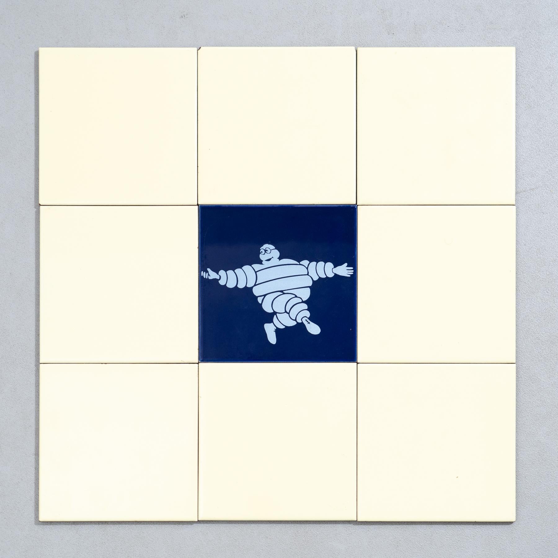 Embark on a journey of vintage charm with this exceptional set of nine tiles, featuring the iconic Michelin Man in a vibrant blue centerpiece, surrounded by original yellow tiles. Crafted by an unknown manufacturer in Spain circa 1960, this set is a