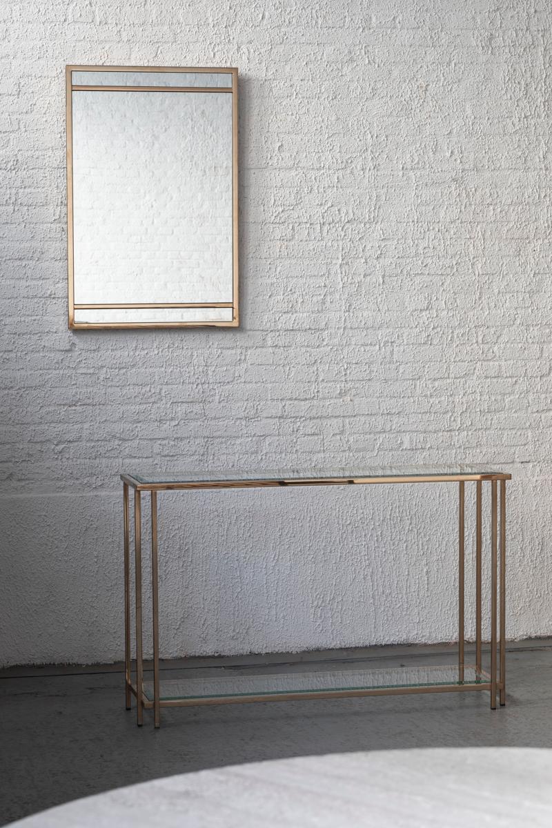 Set of a high console table and mirror, from the Hollywood Regency period, 1970s. The table has a rectangular, brass chrome design with 2 glass shelves. Both panels feature facetted borders. The matching, rectangular mirror is in line with the