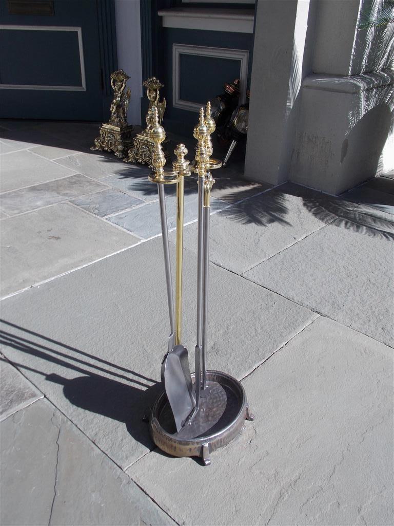 Set of American brass ball foliage finial and polished steel fire place tools resting on oval hammered stand with stylized block feet. Mid 19th Century. Set consist of poker, tong, and shovel.