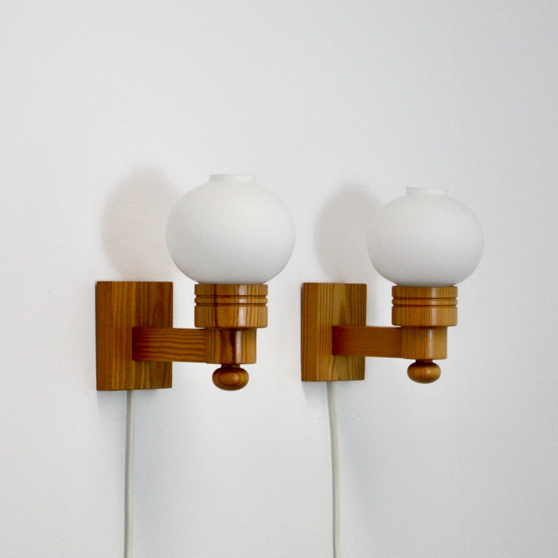 Fine set of Swedish Modern wall lamps in Pine wood and white glass shades. The lamps were made in the 1970s by the Aneta Sweden. 

* A pair (2) of wall lamps in pine wood with white round glass shades
* Manufacturer: Aneta, Sweden
* Year: 1970s
*