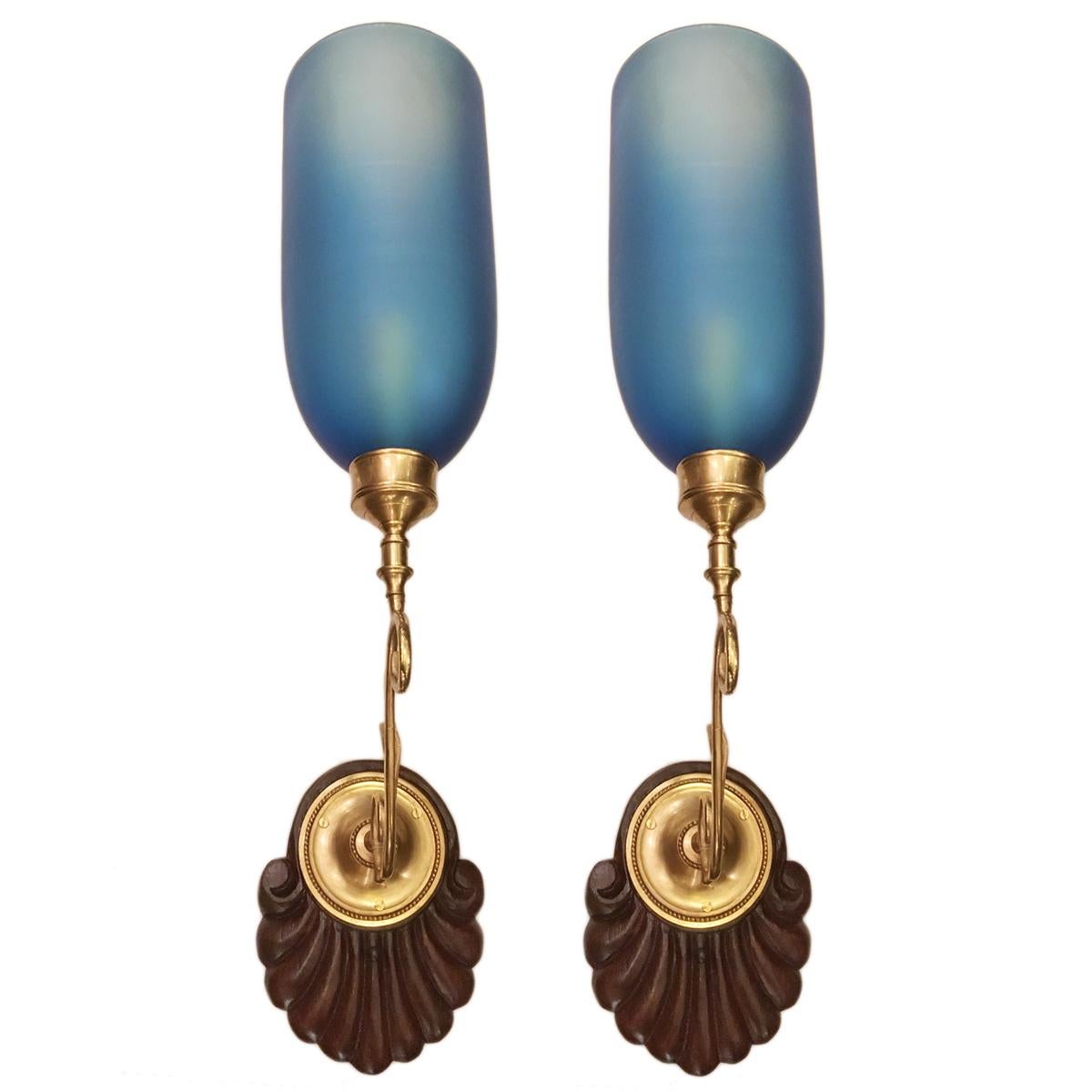 A set of English circa 1950s Anglo-Indian style single-light sconces with carved wood backplates and frosted blue glass hurricanes. Sold per pair.

Measurements:
Height 24?
Width 5.5?
Depth 11.5?.