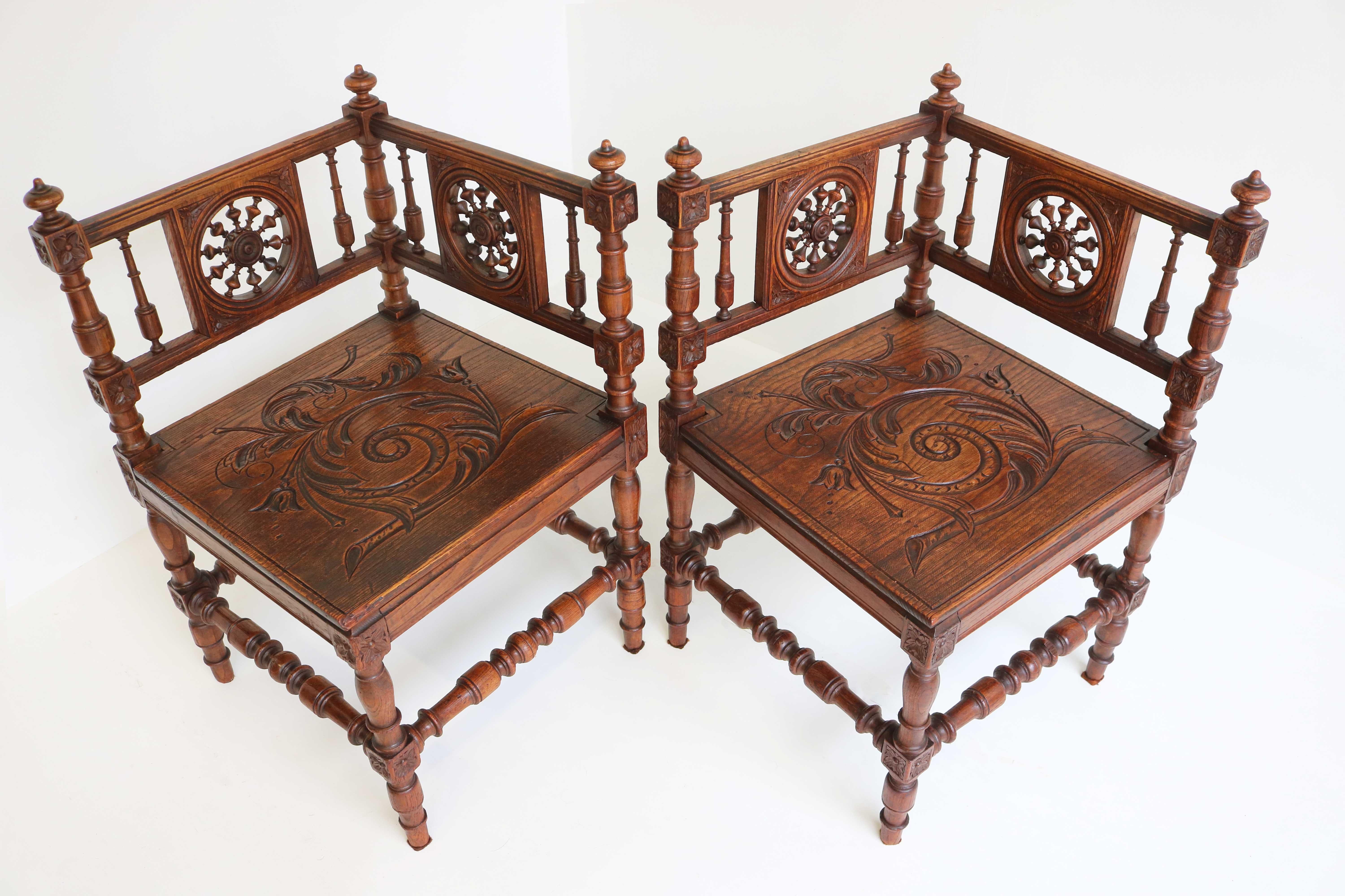 Pair of Breton Brittany renaissance revival corner armchairs in solid oak mid 19th century France. 
Two beautiful provincial style French antique corner chairs made of solid oak, with carved wooden seats, openwork wooden backrests with the