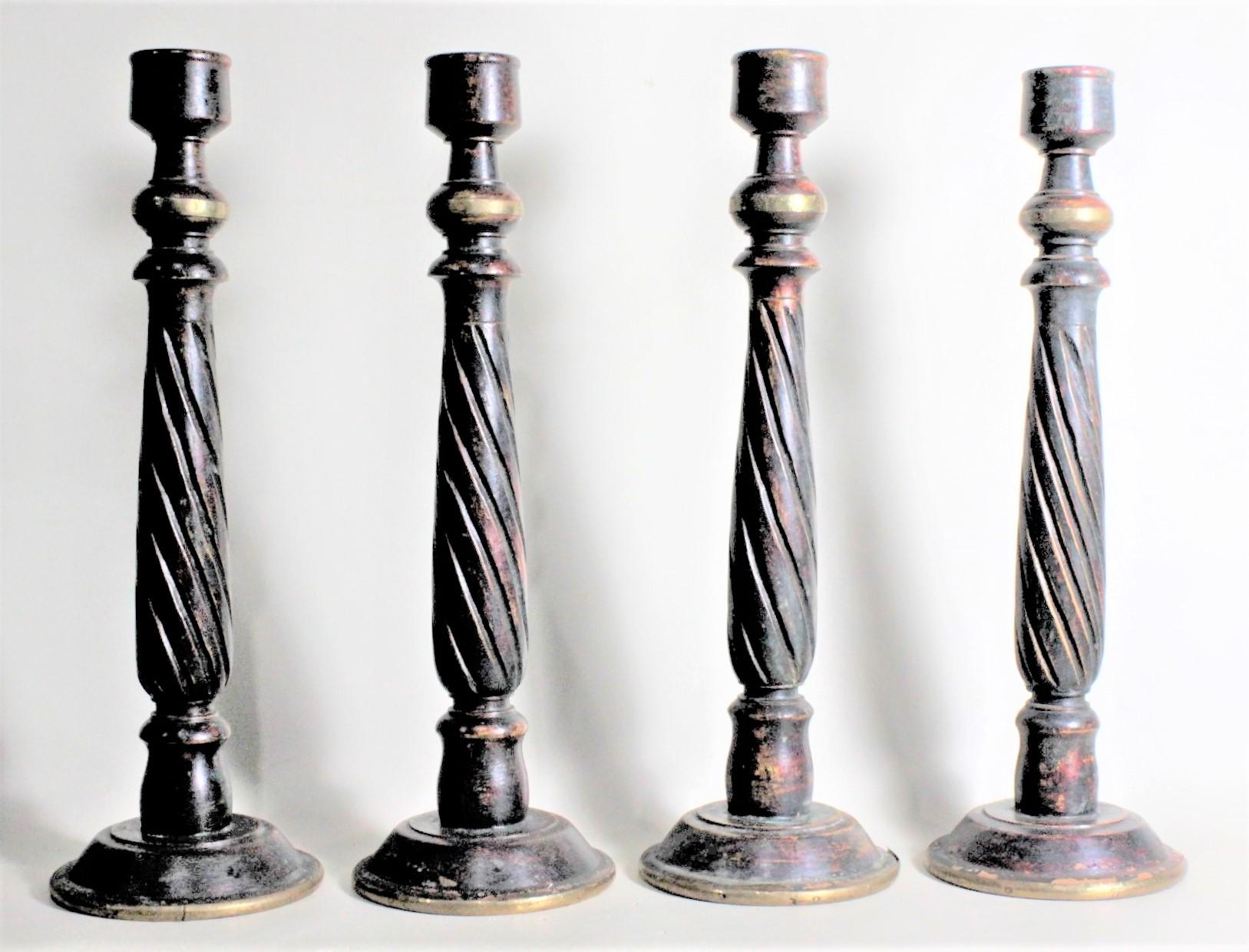 This set of four carved and painted 'cricket stick' styled candlesticks are unsigned but presumed to have been made in Eastern Europe in circa 1930 in a folk art style. The sticks are nicely turned and have carved spiral accents down the body of the