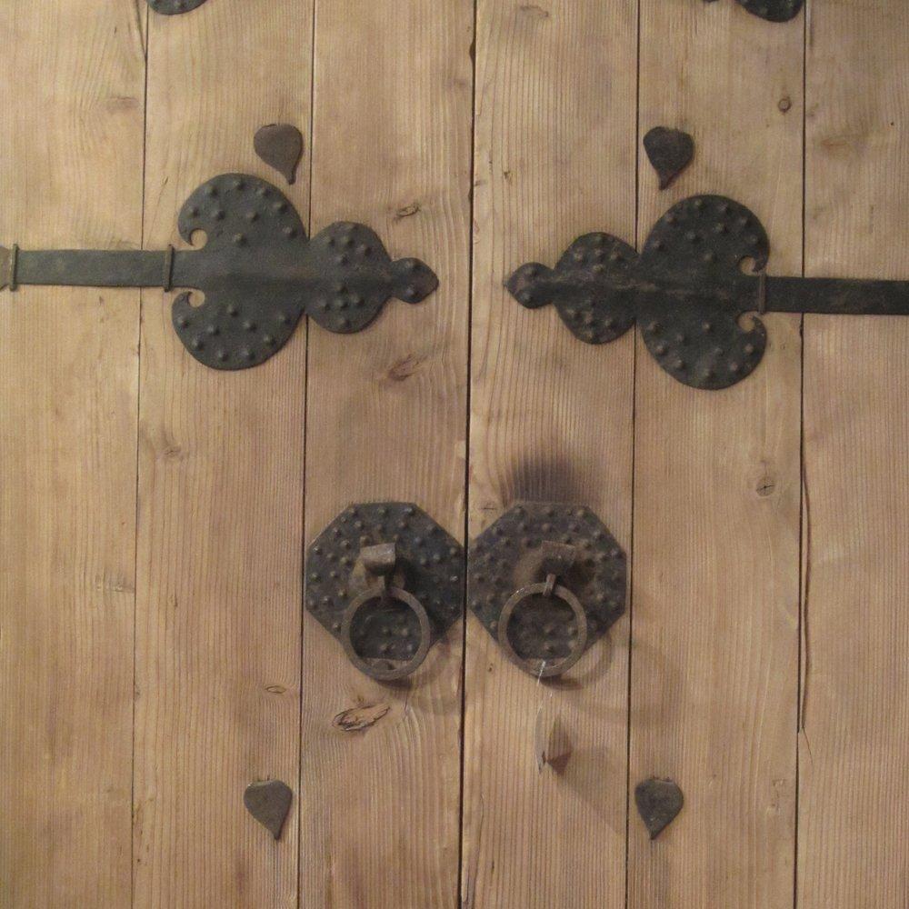 This antique Chinese courtyard door, dating to the late 19th century, showcases a sunbleached finish highlighting its timeworn beauty. The doors are adorned with decorative iron detailing. Crafted from solid wood, the set retains its original