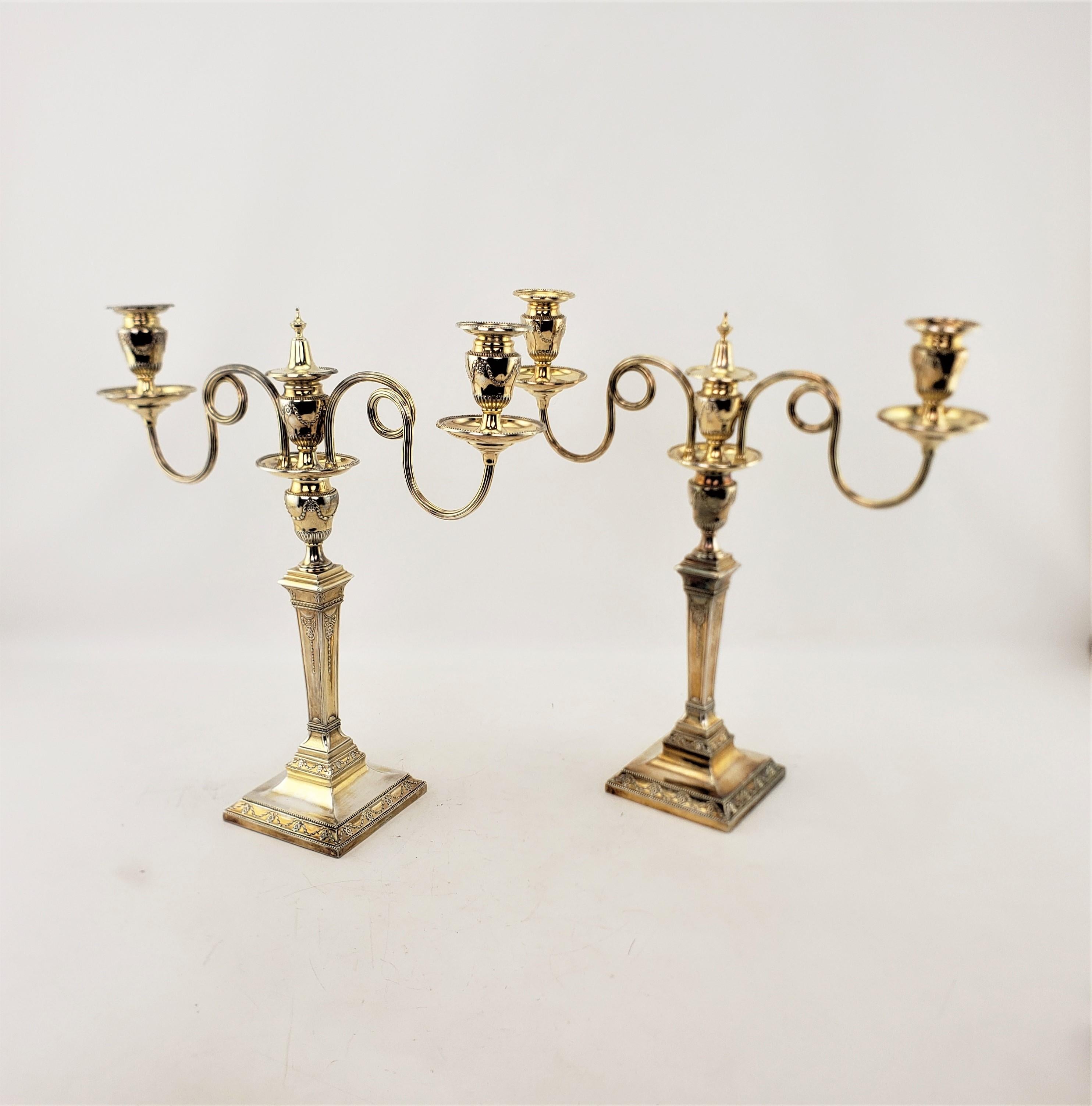 This pair of antique convertible candelabras were made by the well known Mappin & Webb of England in approximately 1900 in the period Edwardian style. The candelabras are composed of silver plate with a gilt finish and decorated with a stylized
