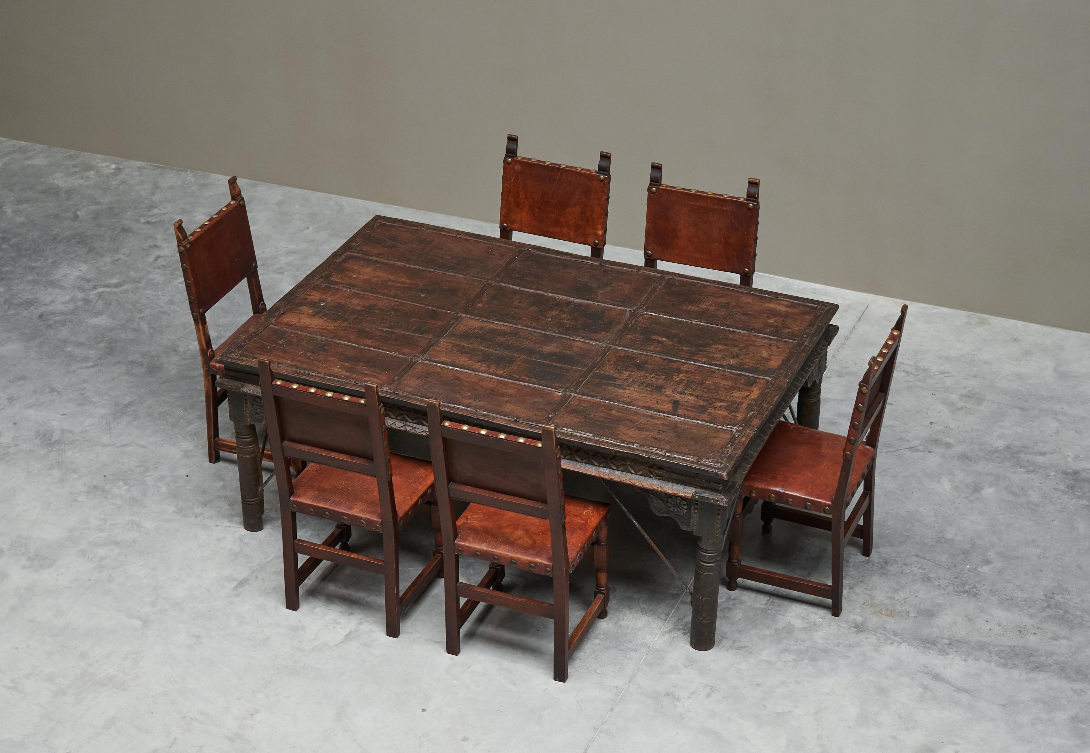 Ensemble de table à manger antique Rajasthan Courtyard Door et 6 chaises en chêne espagnol et cuir

Il s'agit d'une grande table de salle à manger indienne du XIXe siècle, fabriquée à partir d'une porte de cour plus ancienne - probablement du XVIIIe