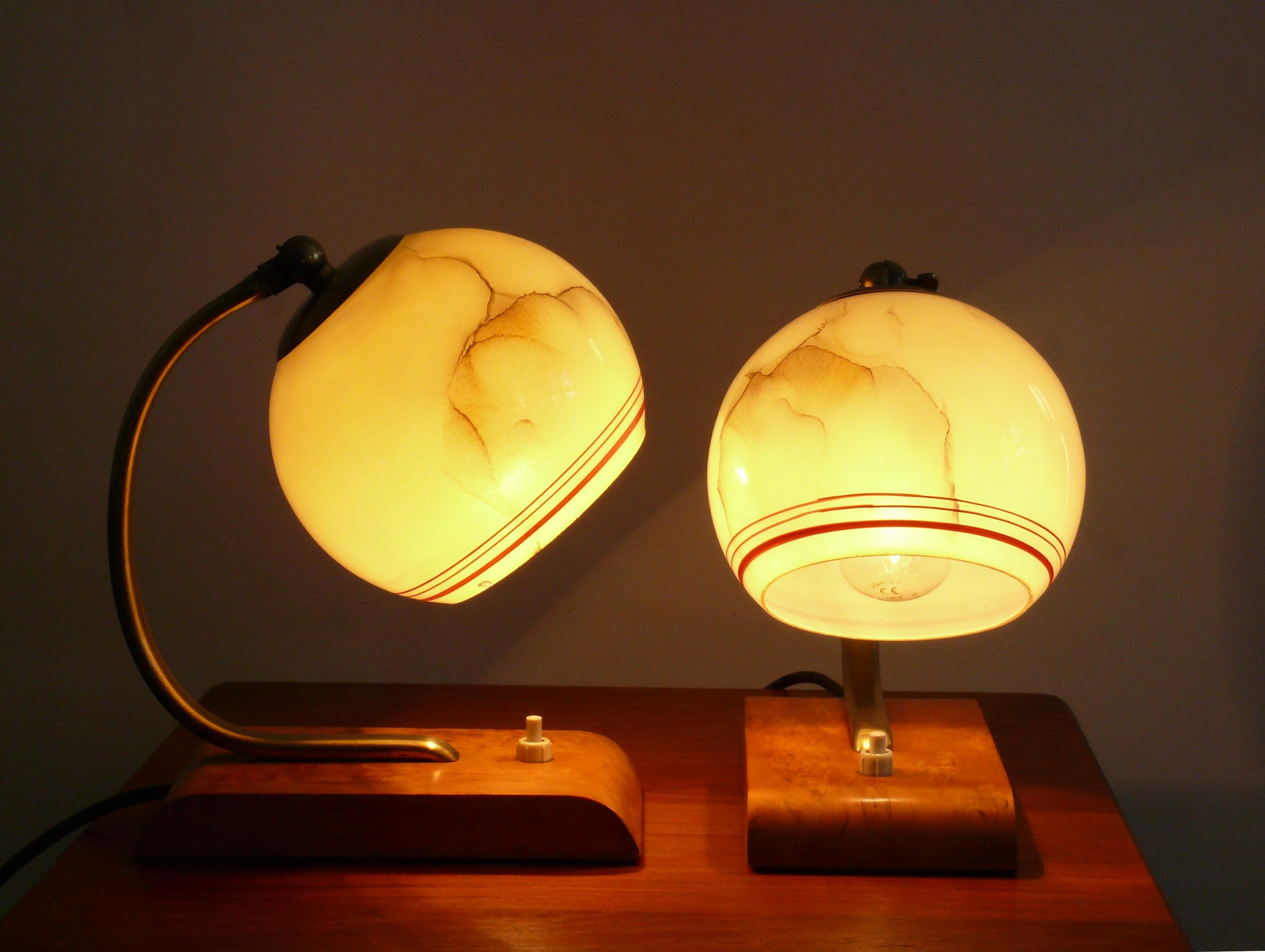 Well-preserved Art Deco table lamps from the 1930s - 1940s. The lights are made of brass and have a yellow spherical shade with radial decorative stripes. The shade can be adjusted via a joint with a knurled screw. Brass frame and ring. The feet are