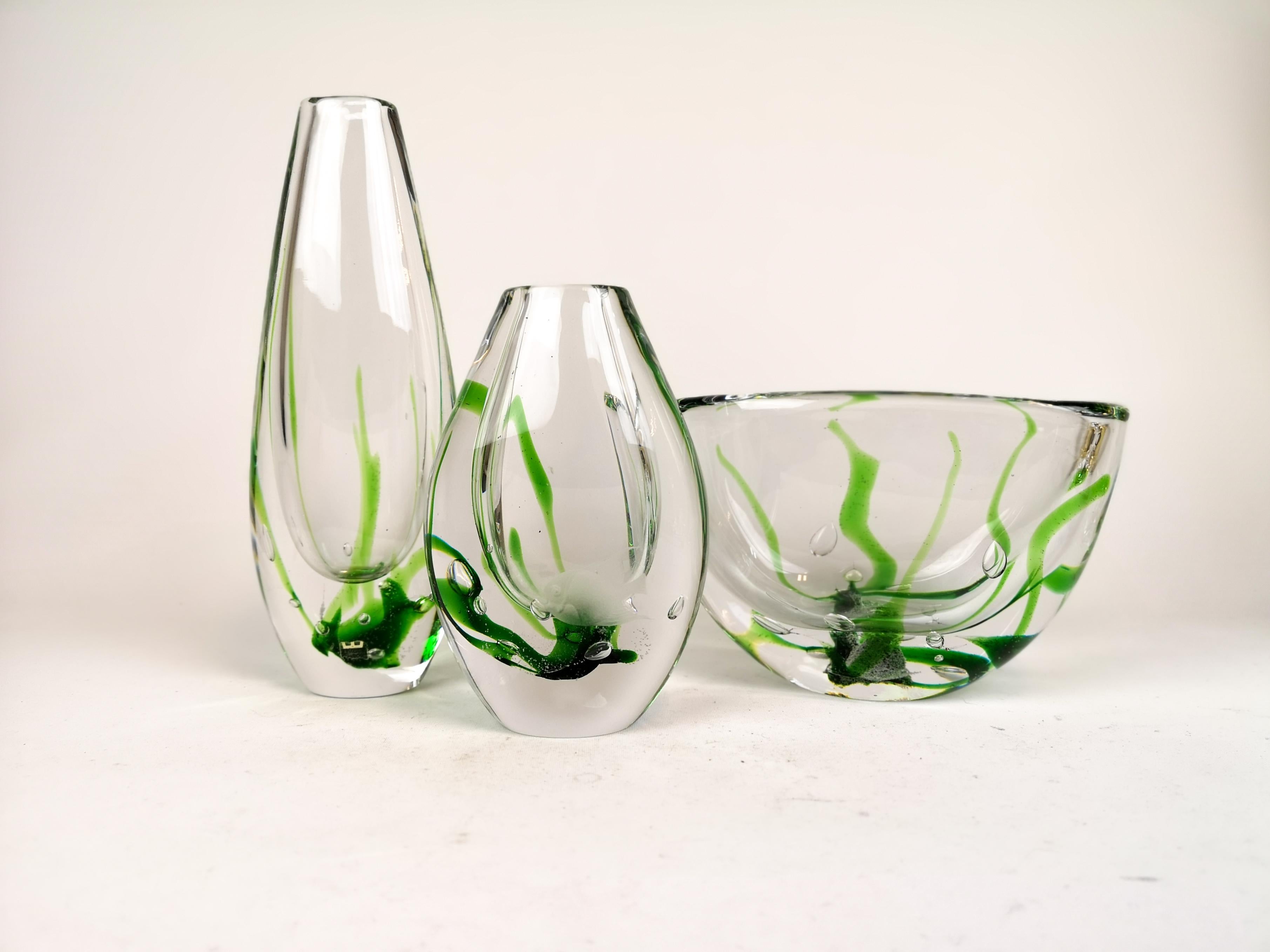 A set of two art vase and one bowl produced in Sweden at the Kosta factory. Designed by Vicke Lindstrand. 
The pieces are made of clear glass with Seaweed inside. These pieces work perfectly together and will create a great atmosphere for where