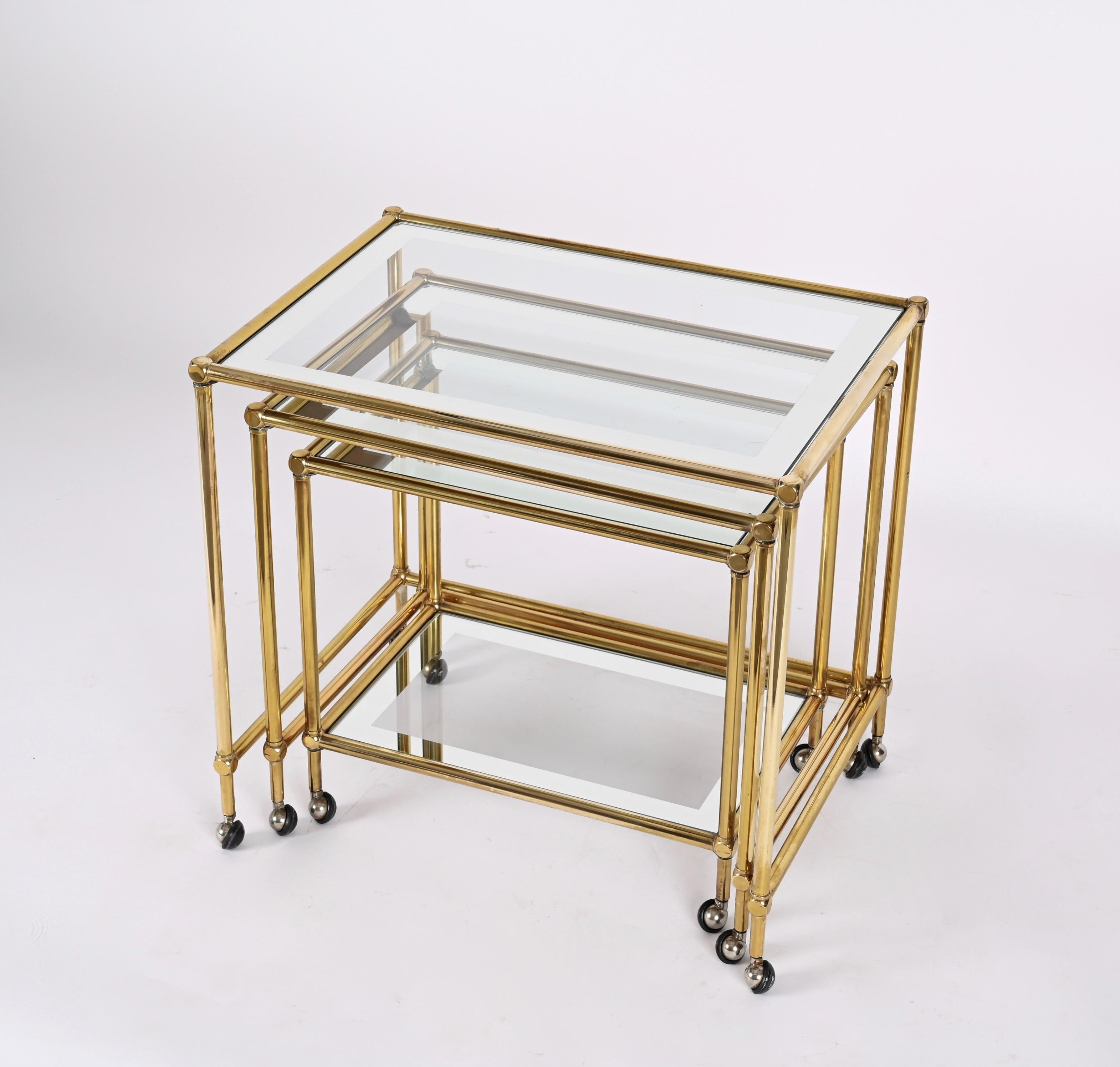 Set of three brass mirrored borders with glass top nesting tables. This fantastic set was designed in France by Maison Jansen during the 1970s.

This set of three small tables with retractable interlocking wheels, glass shelves and a mirror edge