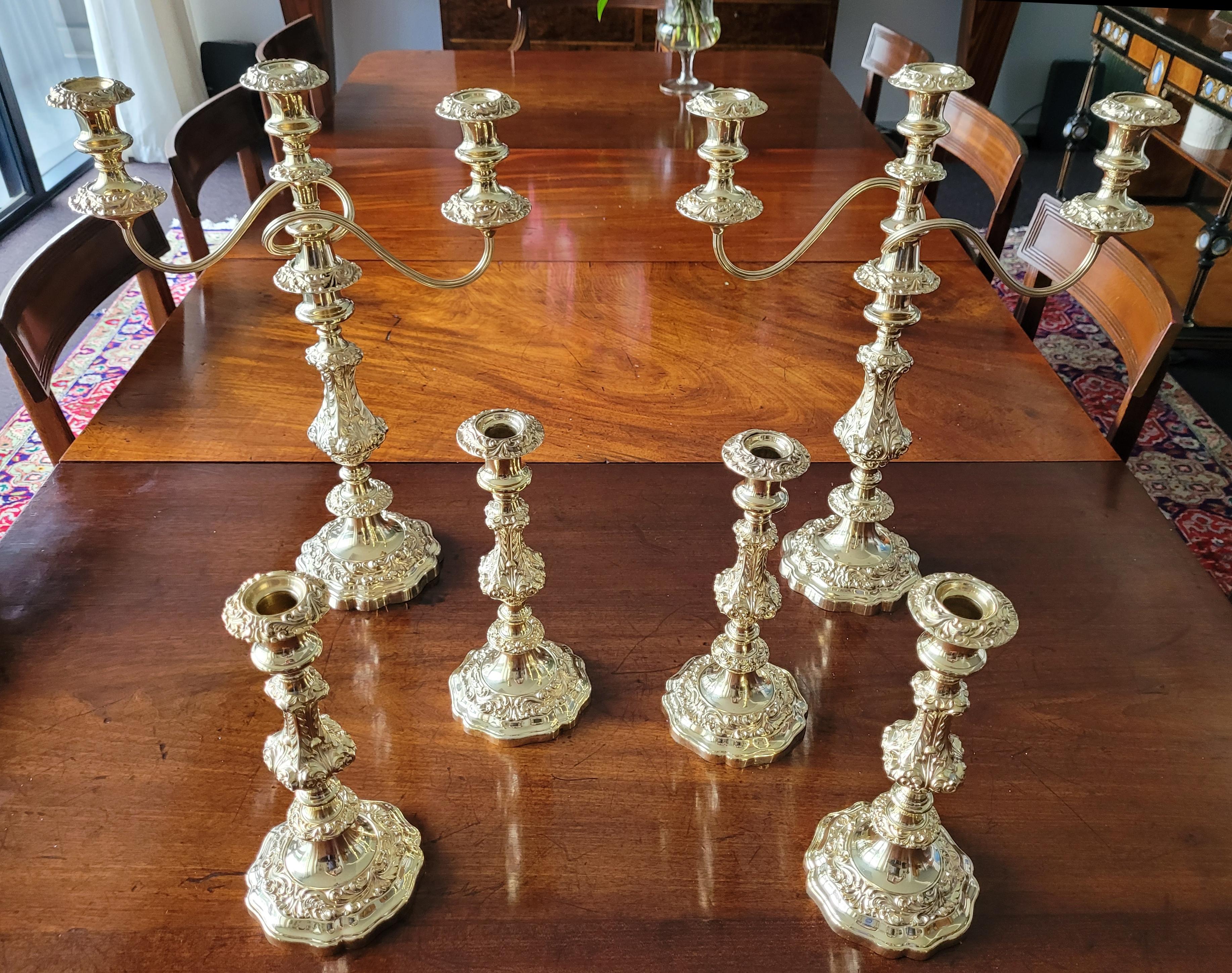 Ein prächtiges vergoldetes Tischset, bestehend aus zwei Kandelabern mit drei Branches und vier einzelnen Kerzenhaltern. Die Kandelaber können durch Abnehmen des Arms zu großen Einzelstäben umfunktioniert werden. Die Bobeches sind zur einfachen