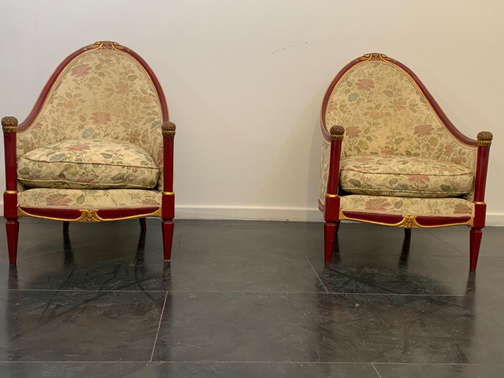 Paire de fauteuils laqués rouge cardinal avec boutons finement sculptés et appliques en feuilles d'or. Recouvert d'un tissu jacquard généreusement épais, il s'agit d'un lampas floral à filaments dorés représentant des pivoines ou des fleurs