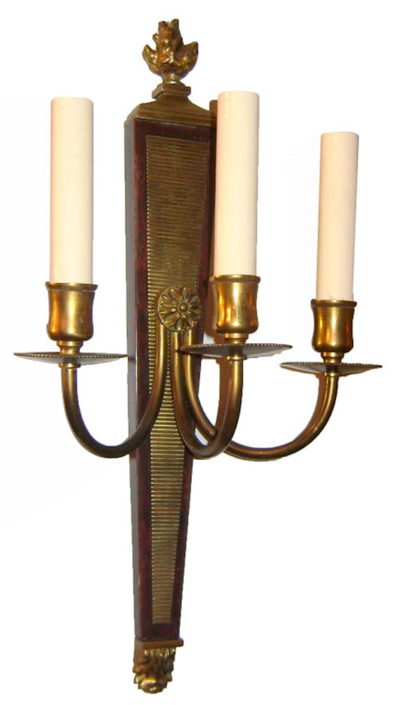 A pair of circa 1920's English neoclassic style carved wood and bronze three-arm sconces.

Measurements:
Height 17