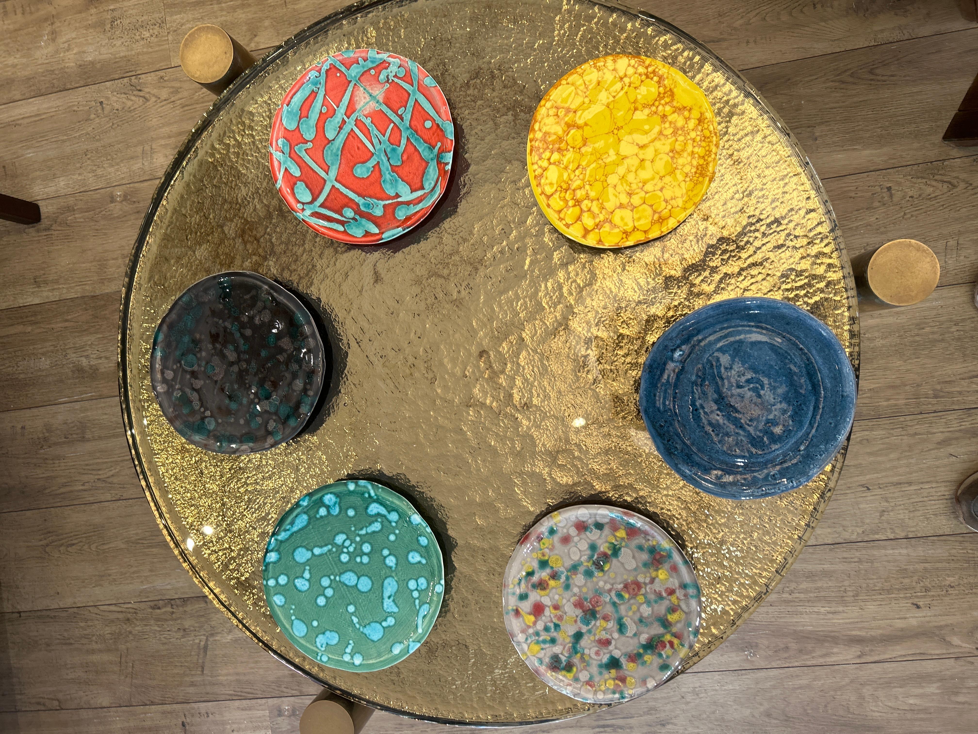 Ensemble de six assiettes en céramique faites à la main, toutes rondes mais avec une grande variété de motifs.
-Assiette rouge vif avec des éclaboussures et des lignes turquoises
-Plaque noire et verte foncée avec des mouchetures bleu-vert
-Plaque