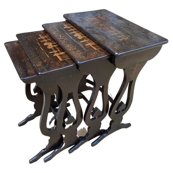 This Set of 4 nesting tables are Chinese Export market in the truest sense. Black Lacquered background is nicely painted in a landscape with pavilions. This is surrounded by a delicate border of stylized scrolling leaves. The shaped tops are raised