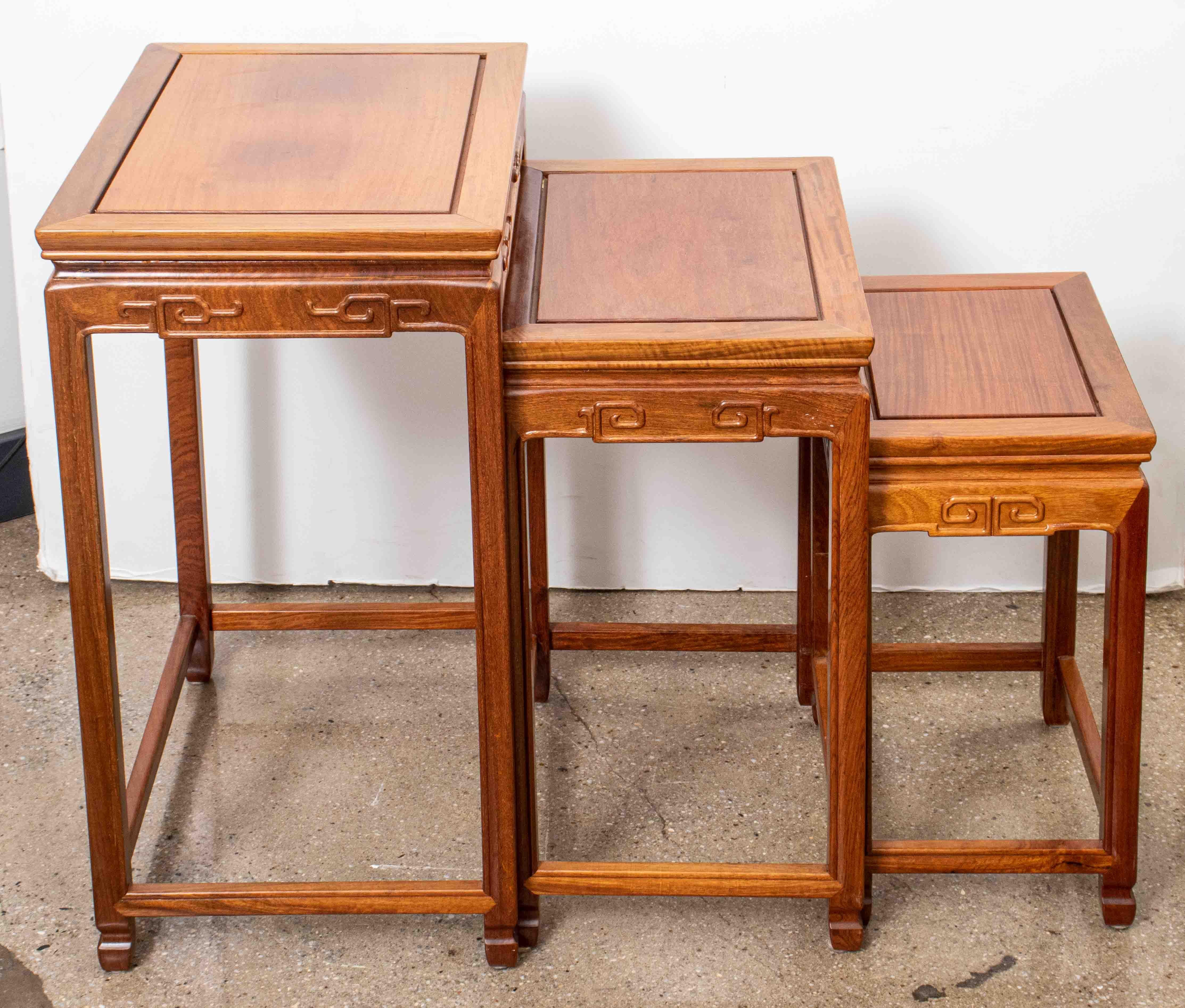 Set of three Chinese golden-honey-tone hardwood nesting tables, each with carved scrolling design upon apron and four slender legs. 
Largest: 26.25