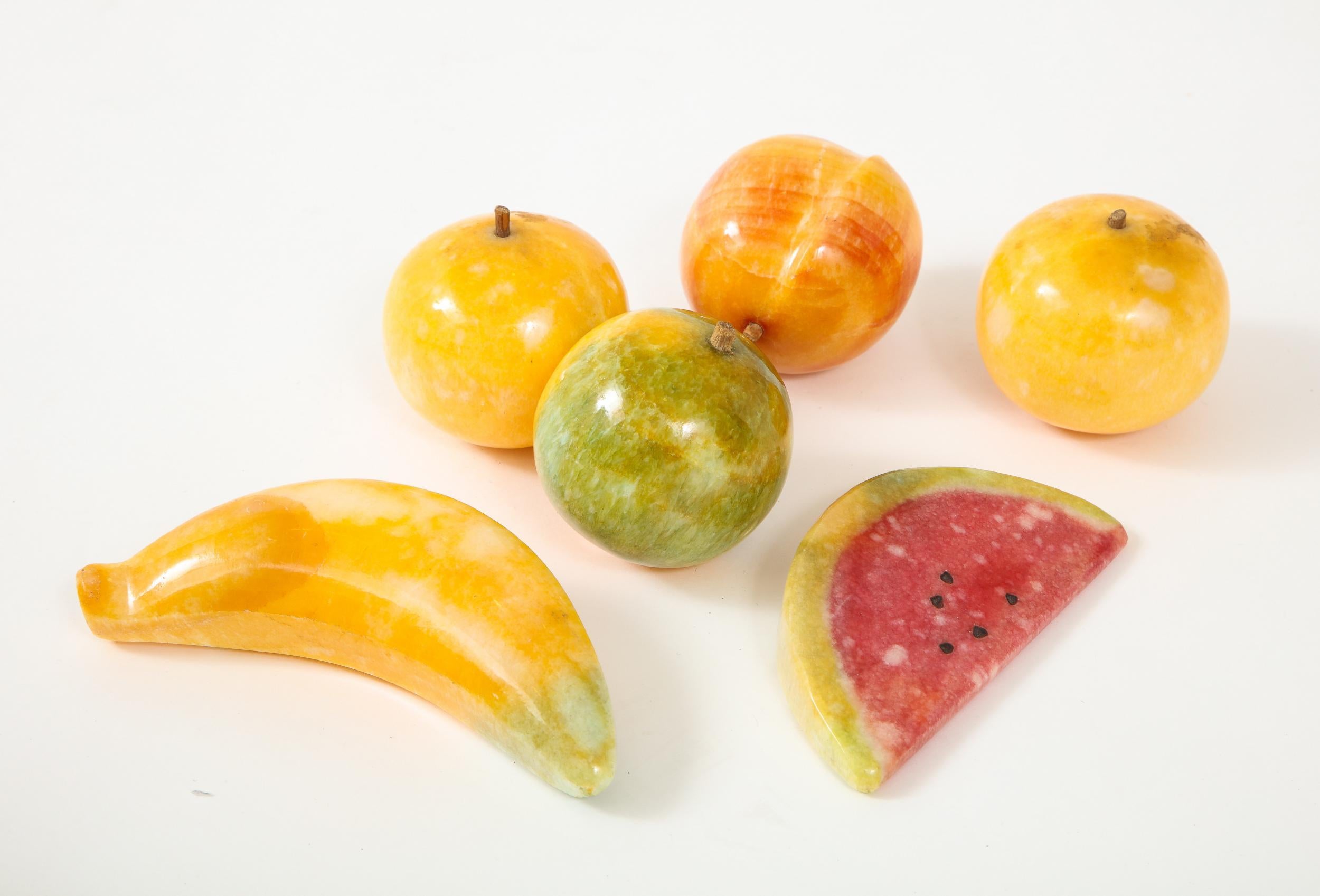 Stone fruit has long been a decorative object across many different artistic periods. This polished set is from the 1970s and includes a highly desirable banana and watermelon as well as one peach, one green apple, and two oranges. Peach and oranges