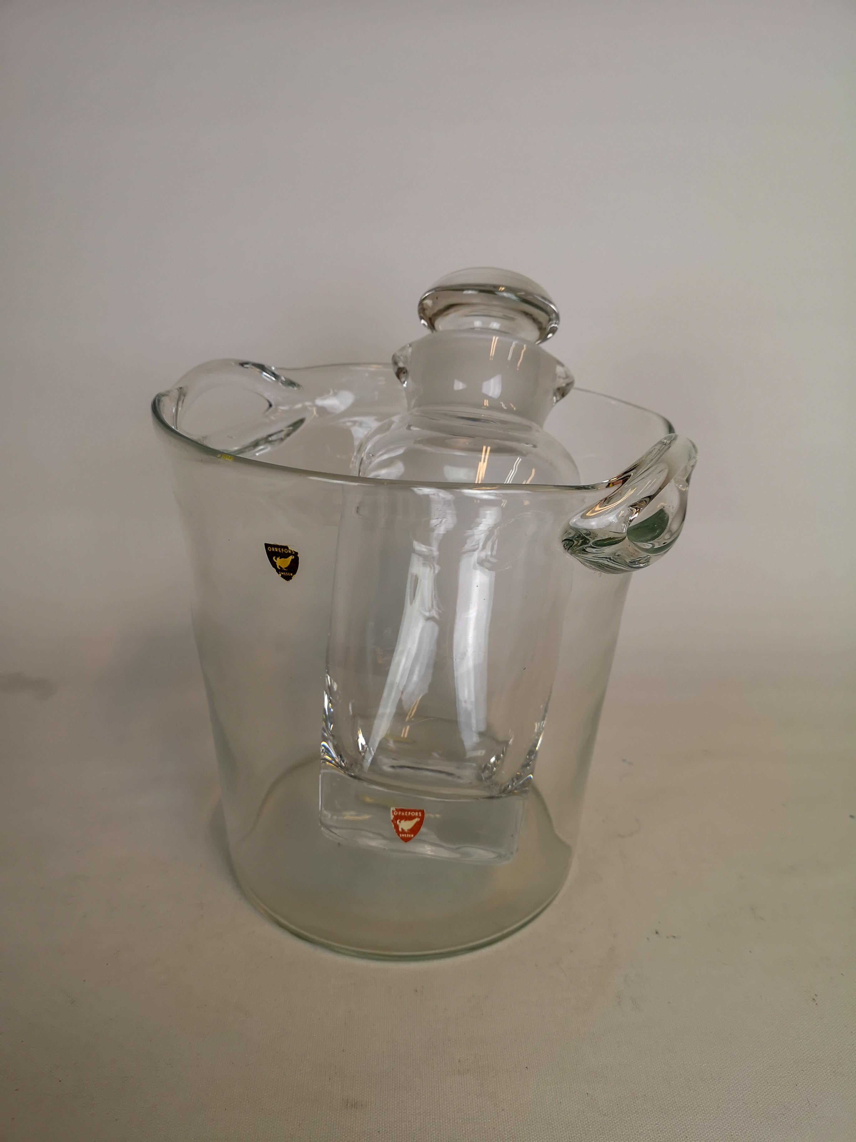 This set contains a glass bucket for ice or vine cooler. The other piece is a Shaker/carafe for spirits/whiskey. They are both designed by Nils Landberg and manufactured at Orrefors in the 1950s.

Good condition

Measures: Bucket H 19 cm D 20 cm
