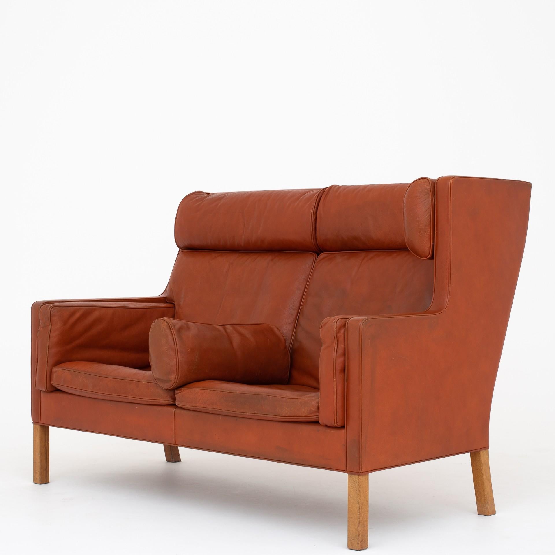 Coupésofa in a rare corner module-edition, consisting of a right and left turned 2-seater sofa in original red/brown leather with legs in mahogany. BM 2192. Maker Fredericia Furniture.