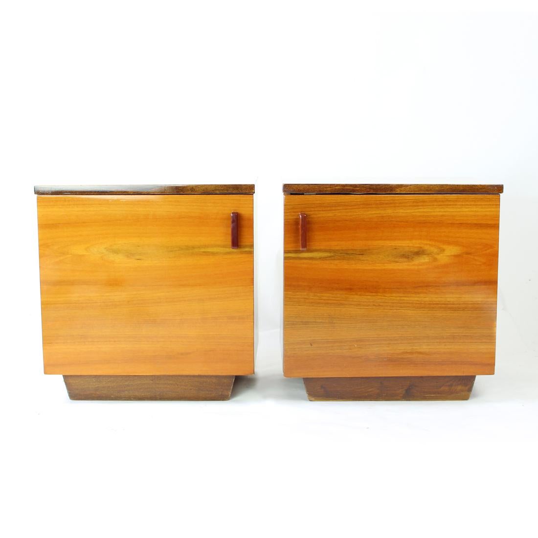 Beautiful set of two vintage bedside tables produced in the mid-century modern period of design. Produced in Czechoslovakia in 1960s. The tables are made of cubical shape with one plain door opening and original shelf inside. The tables are finished