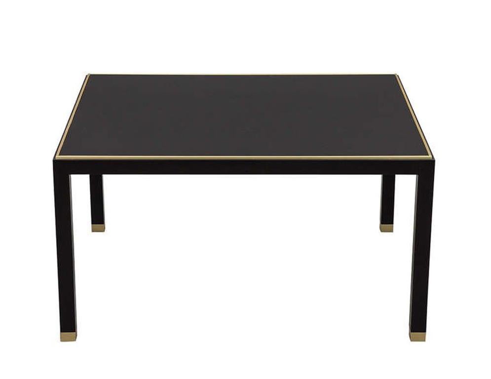 Custom-made by Carrocel Modern Art Deco Inspired coffee cocktail table and end table set of two-piece. Finished in a hand polished black lacquer with a solid brass top insert trim detail and accent legs with a black back painted glass top inset