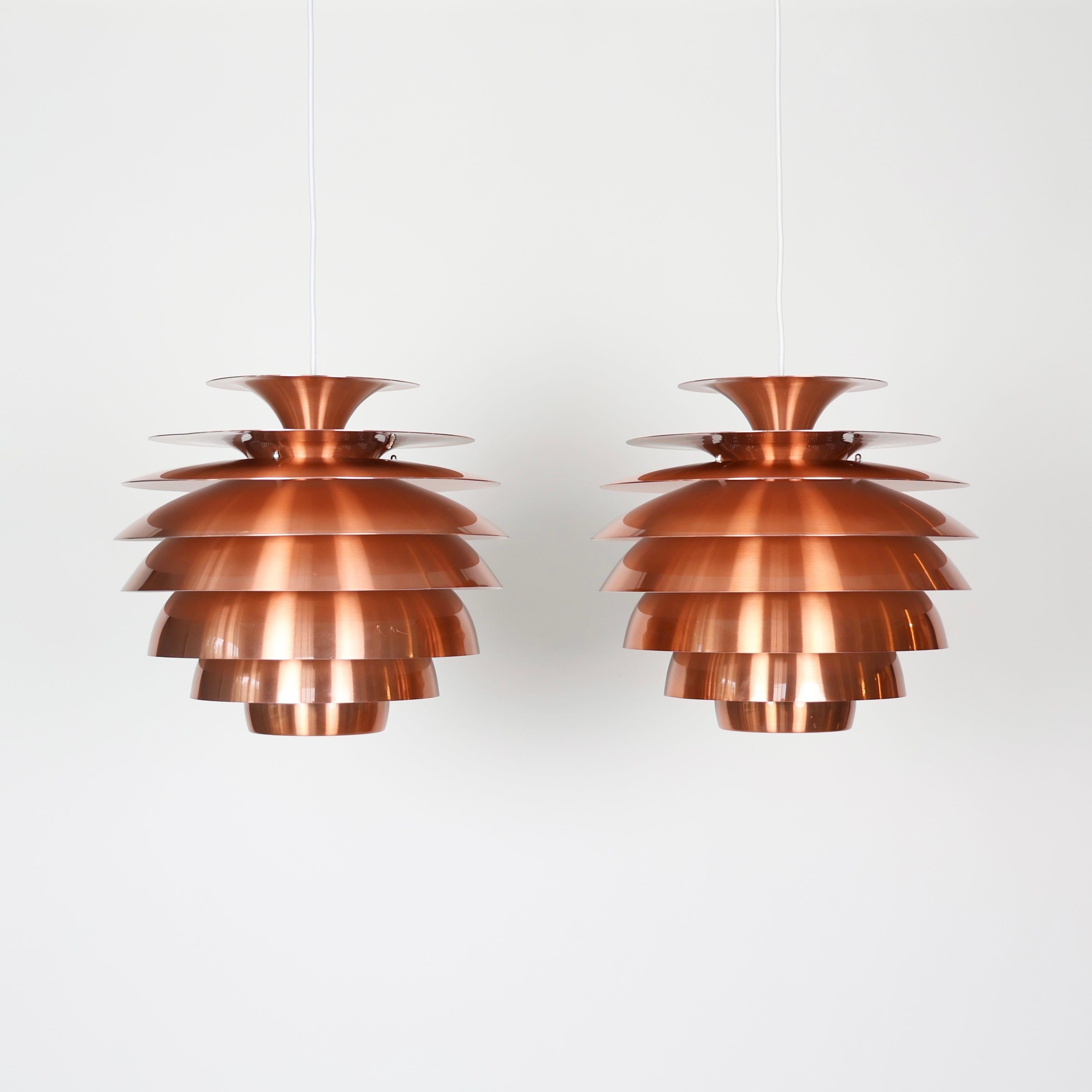 Set of Impressive Danish Copper Pendant Lights made in the 1980s

* Set (2) of pendant light with multi-layered copper lacquered metal slates.  The copper color has almost a pink shine. White on the inside. 
* Country: Denmark
* Style: Barcelona
*