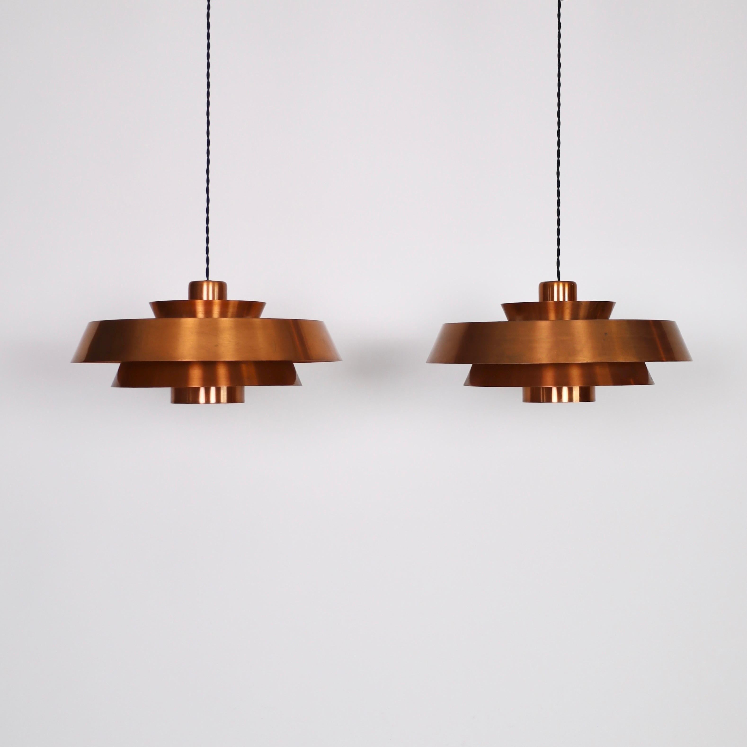Set of Copper Pendant lights designed by Jo Hammerborg for Fog & Mørup in the 1960s. A fine duo for a beautiful home.

* Set (2) of copper lacqured pendant lights. Orange / white on the inside.
* Designer: Jo Hammerborg
* Model: Nova
* Producer: Fog