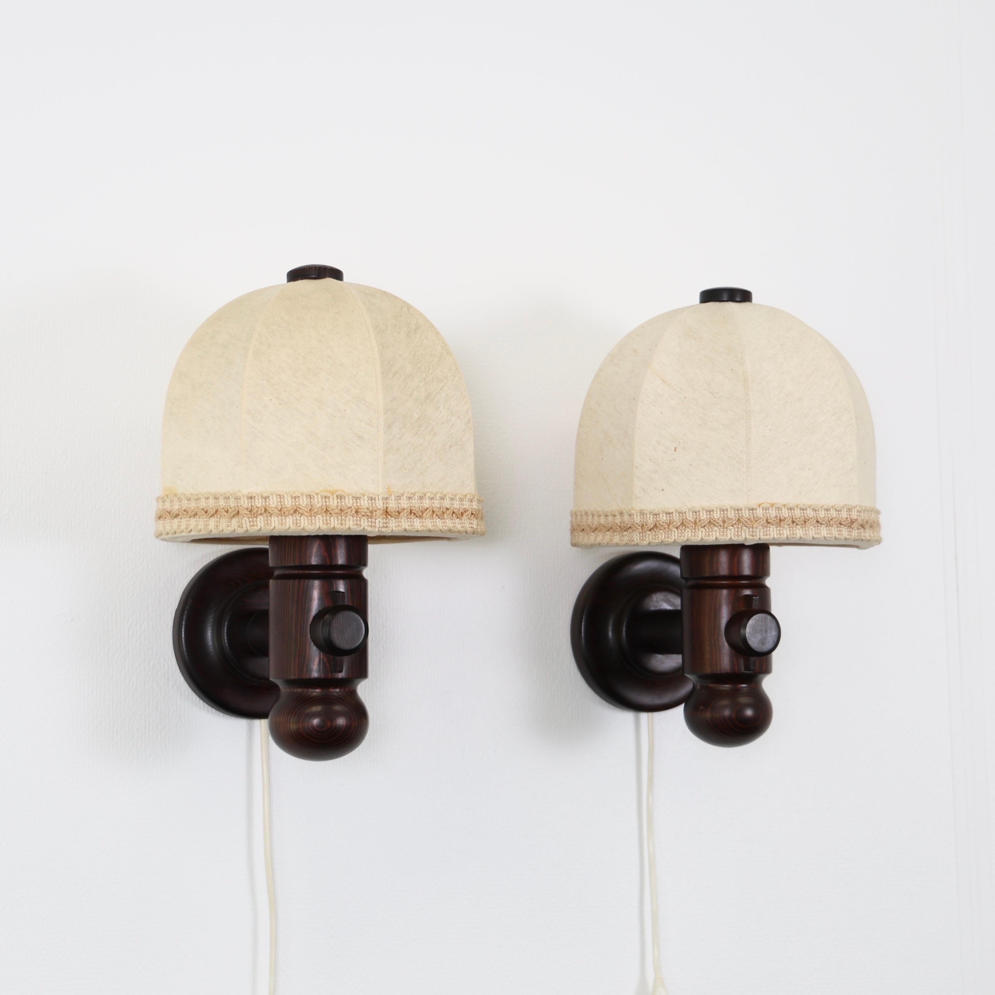 Set of Dark Stained Pine wood Wall Lamps with the Original Shades designed by Jan Wickelgren for Aneta in the 1970s. A fine Scandinavian duo. 

* Pair (2) of wall lamps in dark stained pine wood with fabric shade.
* Designer: Jan Wickelgren
*