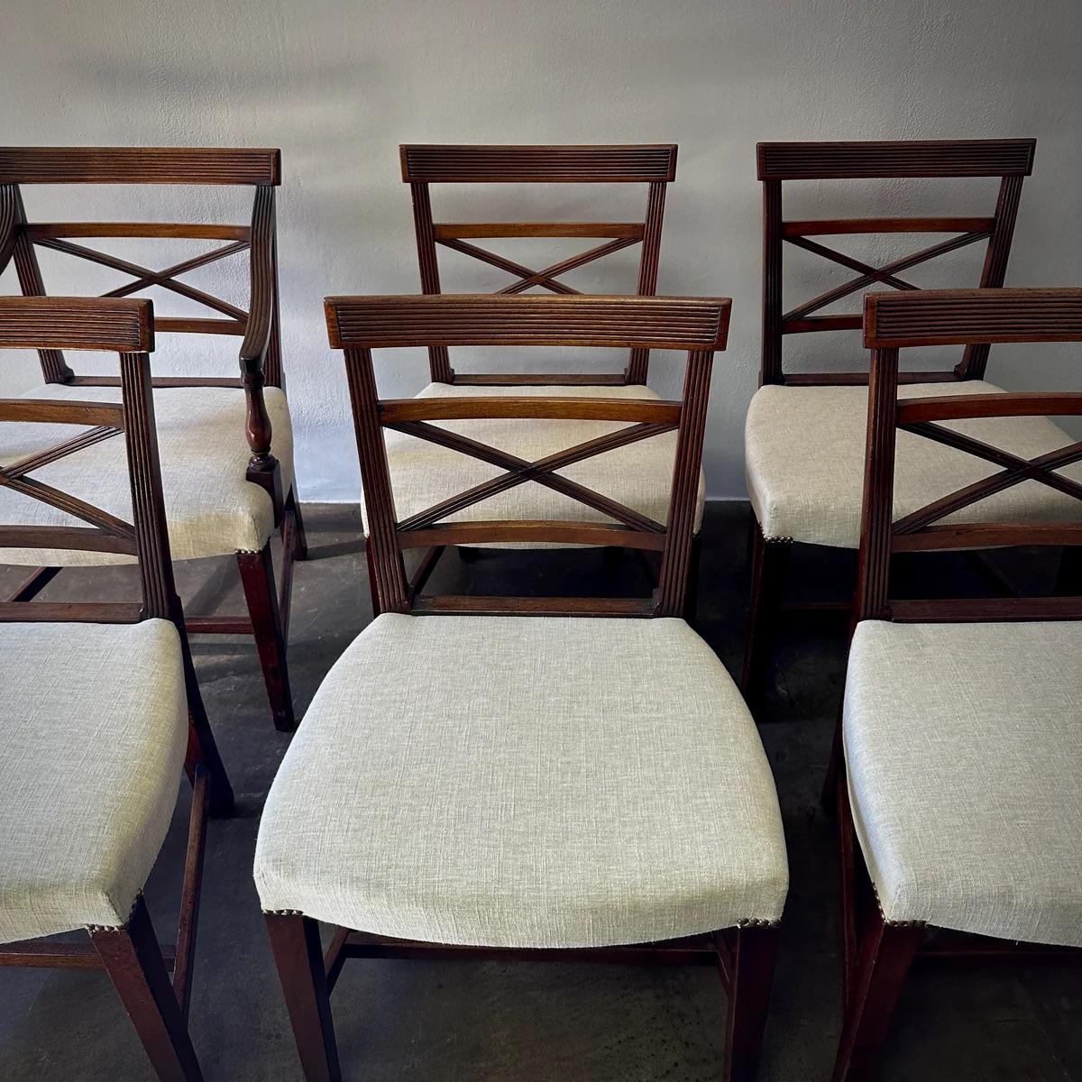 Cet ensemble de huit chaises de salle à manger en acajou d'Angleterre comprend six chaises d'appoint et deux fauteuils, chacun présentant un dossier croisé texturé et des sièges rembourrés. Les détails raffinés et les riches tons de bois des chaises